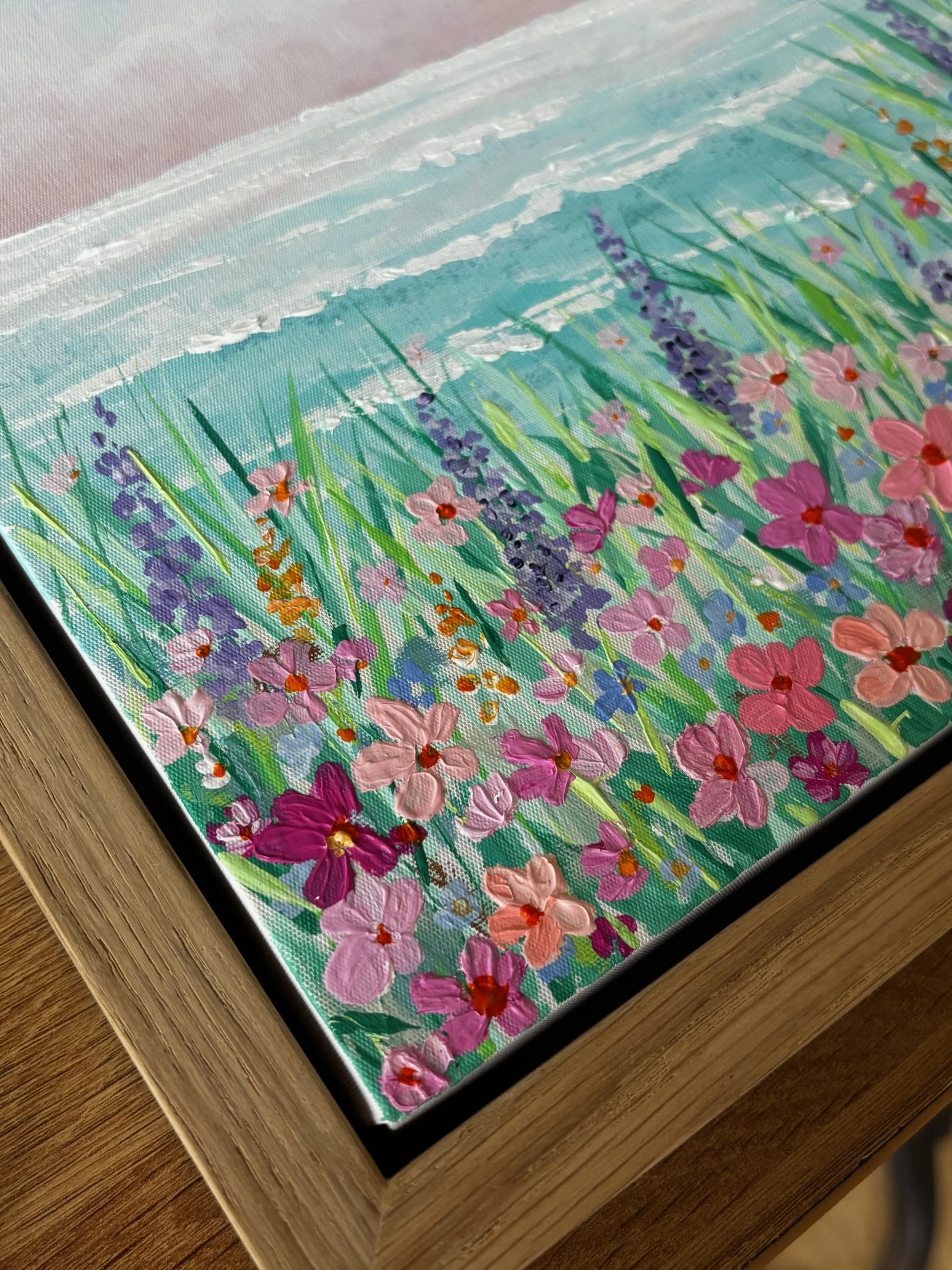 Alt Text Seascape I original coastal landscape painting with soft pink skies turquoise ocean and wild meadow flowers in oak veneer frame