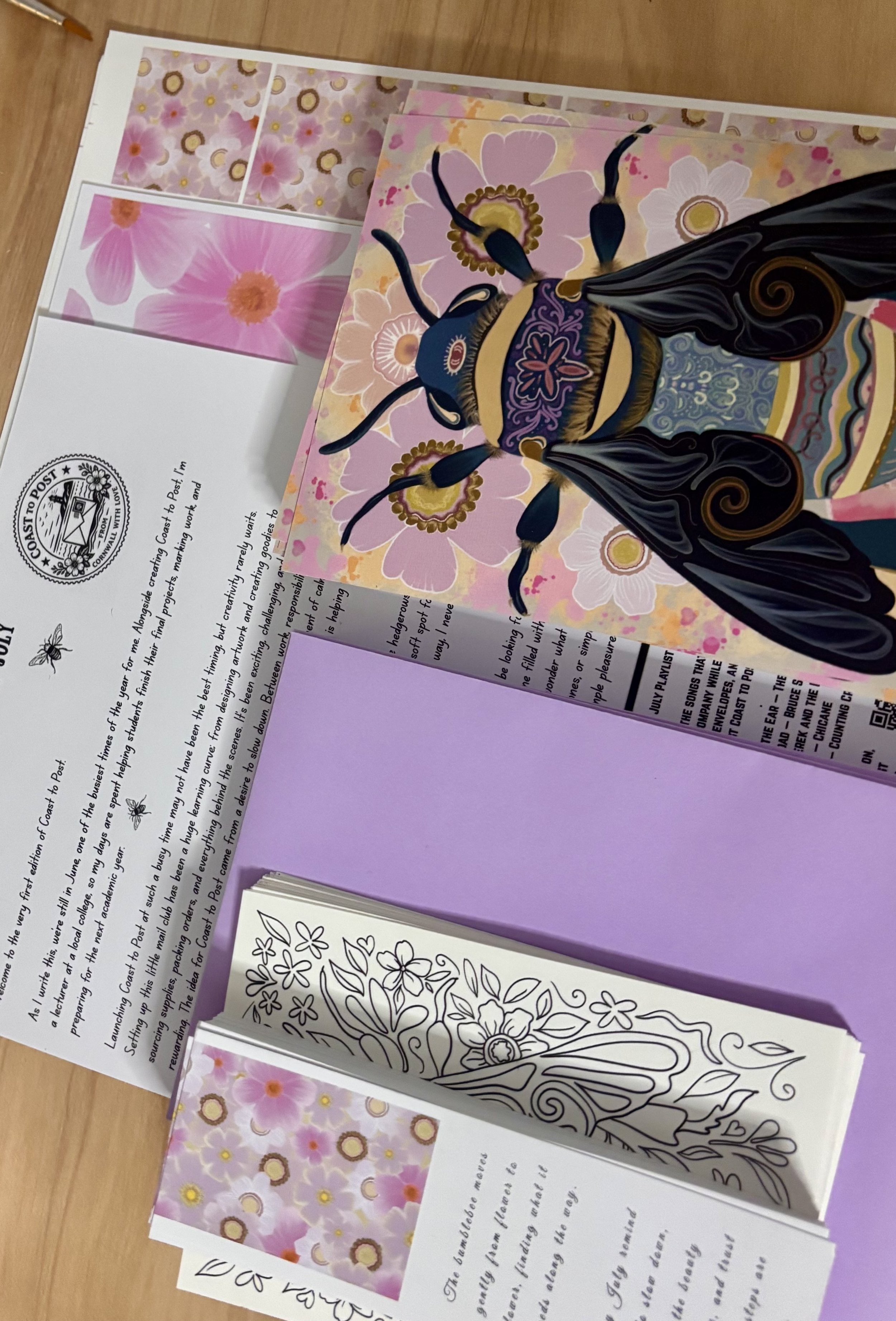 Colorful art print of a bee with floral background, pink, yellow, and purple colors, surrounded by sheets of paper with floral patterns and handwritten notes. Mailclub, postal subscription, art, snailmail, penpal. Printclub