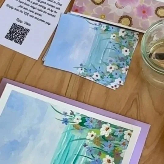 Close-up of floral-themed paper or cards on a wooden surface, with a glass jar and printed papers nearby.
