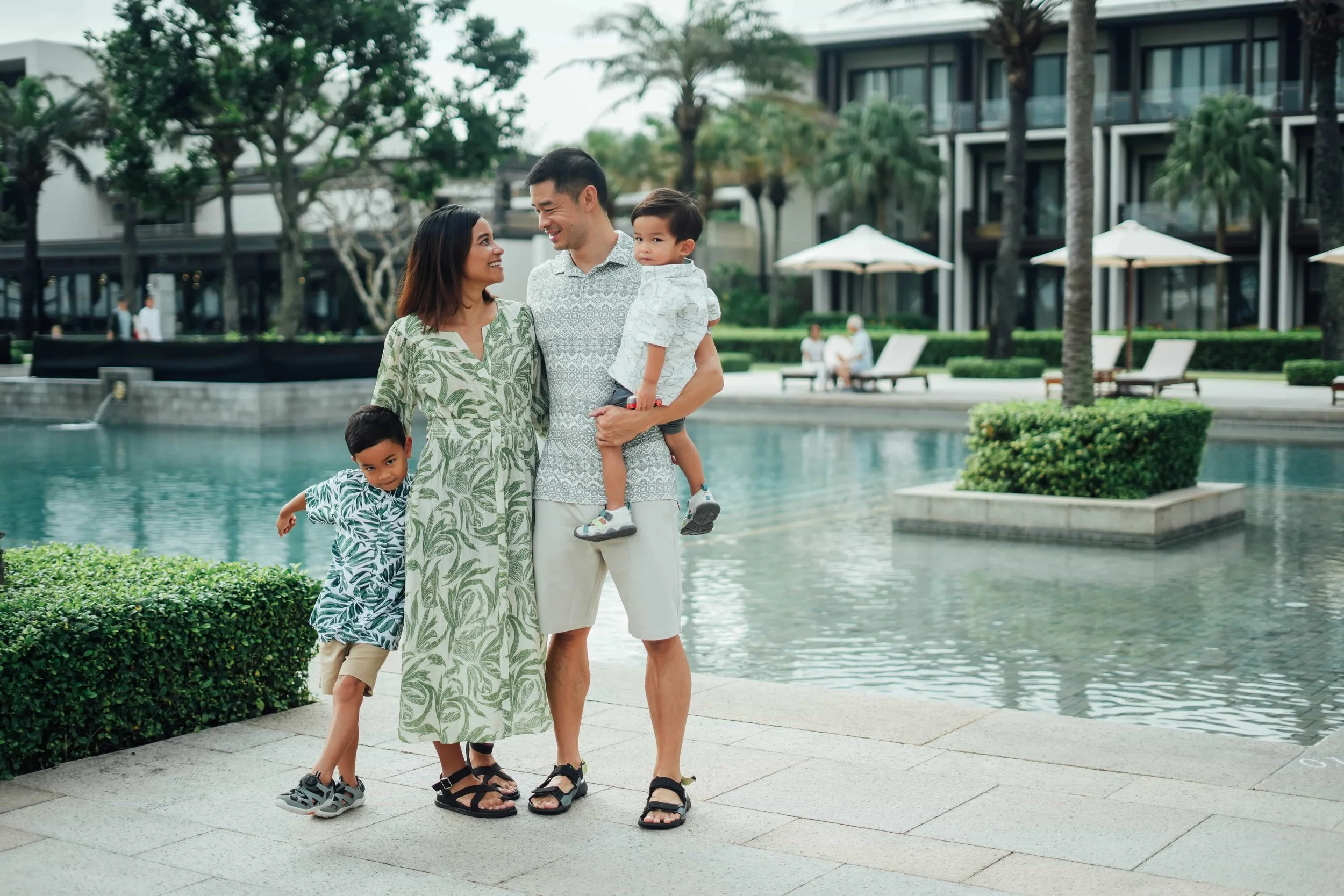 A family of four standing by a water fountain in an outdoor area with green trees and modern buildings in the background. Destination Branding and Placemaking Asia