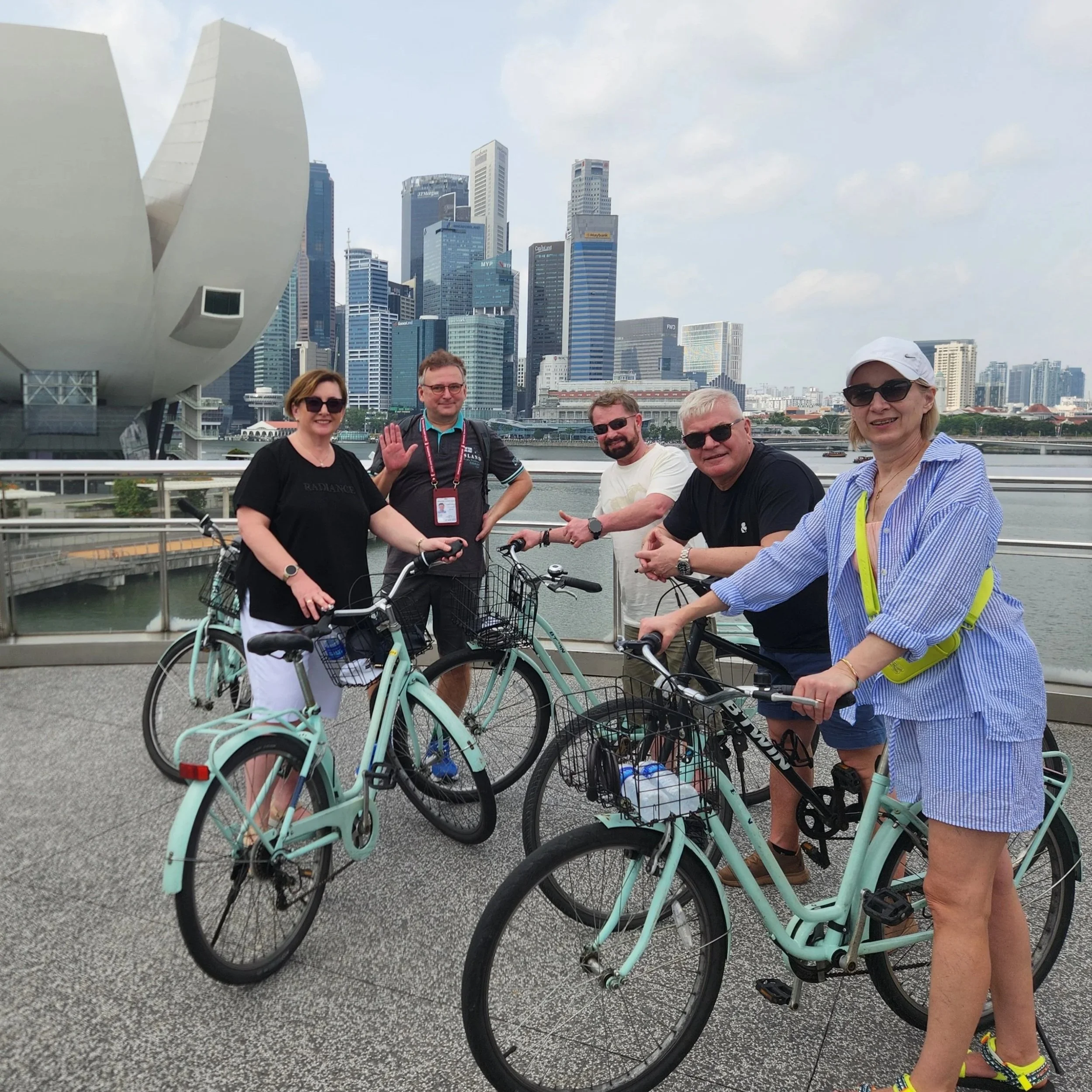 Group of tourists with bikes at waterfront overlook in downtown Singapore with skyscrapers in the background