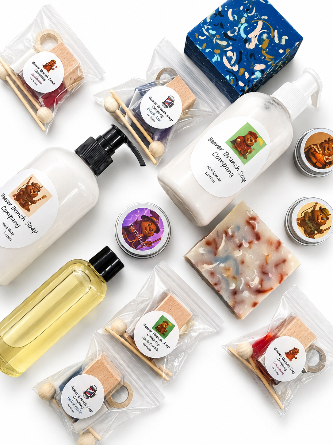 Assorted handmade soap and lotion bottles labeled 'Beaver Branch Soap Company' with beaver-themed labels, packaged soap bars, and car freshener bottles arranged on a white surface.