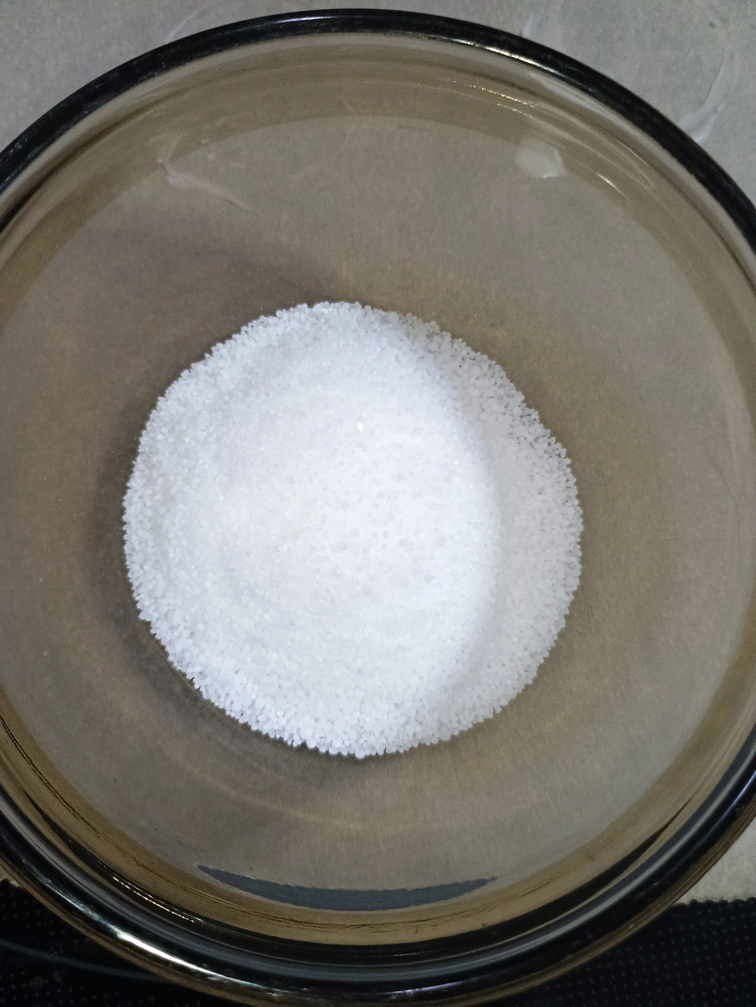 White Urea crystals inside a glass bowl, seen from above.