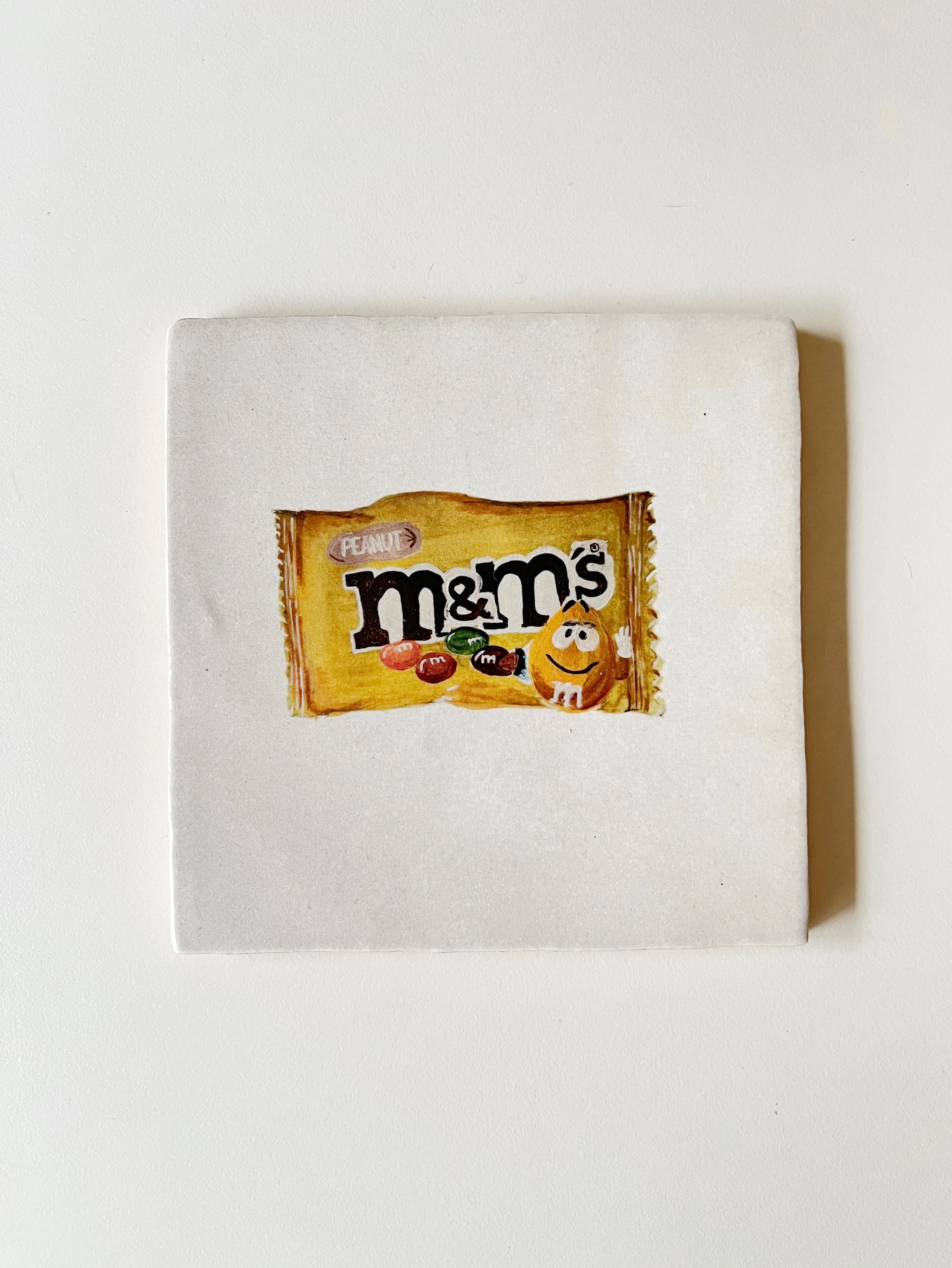 Ilustración sobre azulejo de una bolsa de chocolates m&ms creado Bylajuana