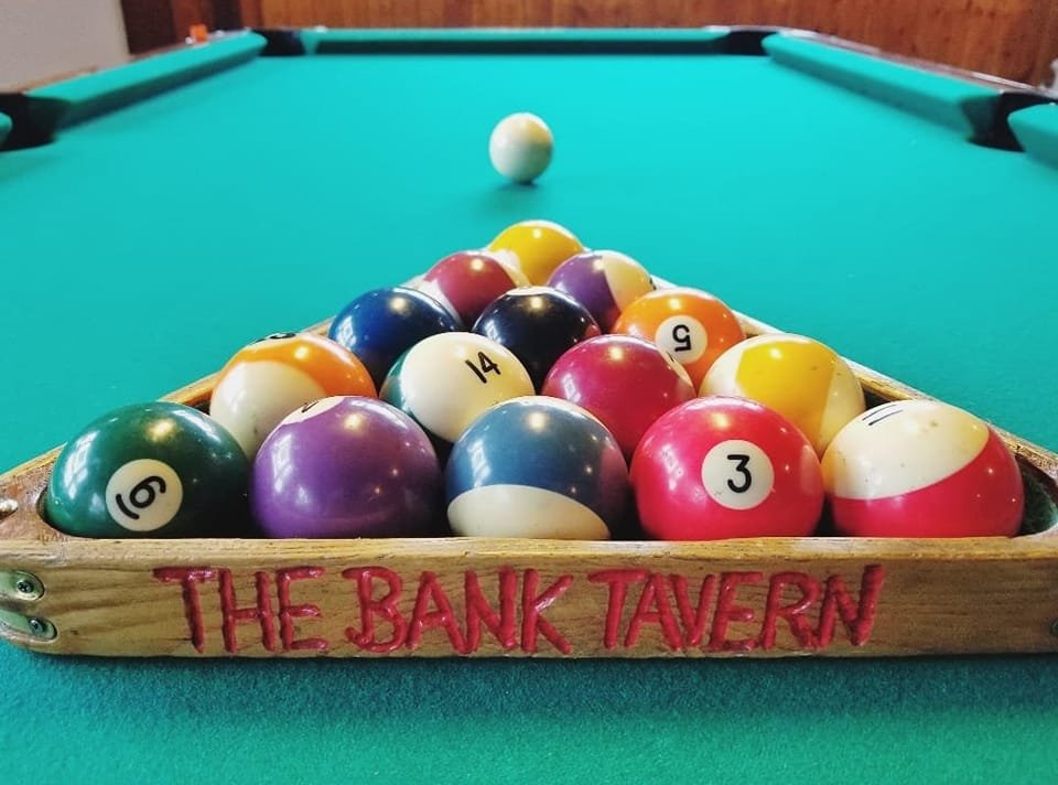 Pool table with a rack of billiard balls and an overhead cue ball.