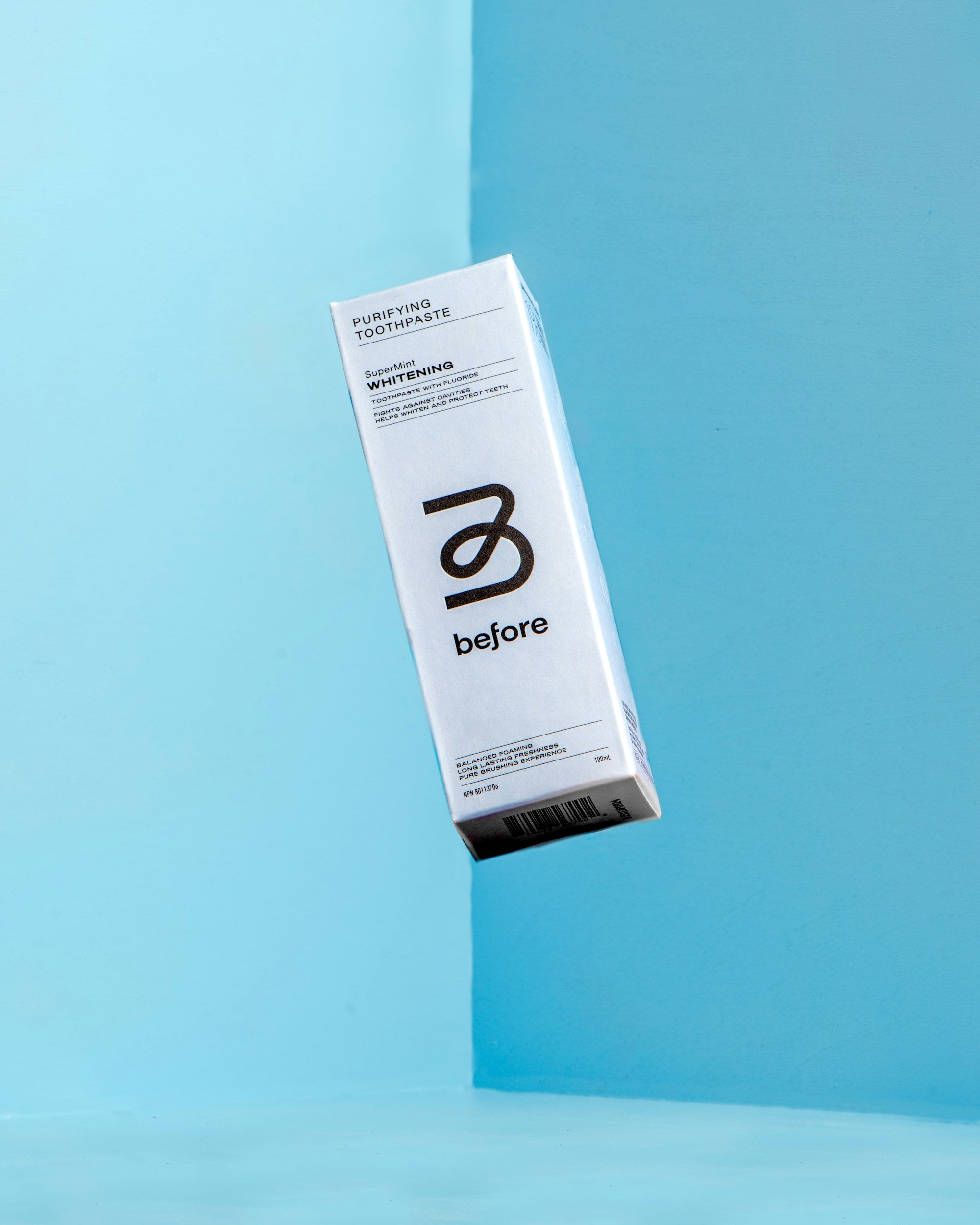 A white box of purifying toothpaste with blue text and black lettering, set against a blue background.