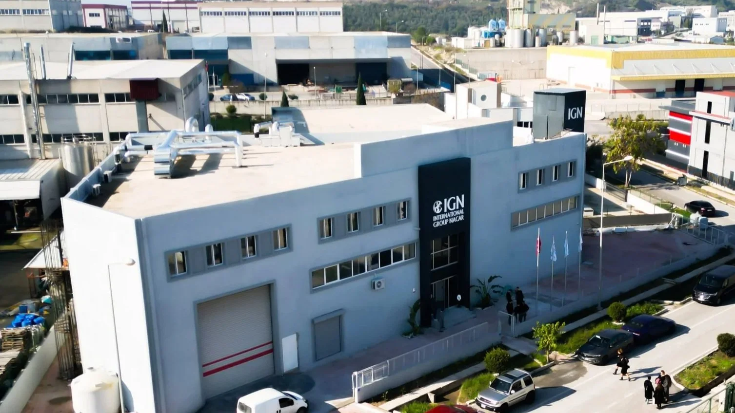 Aerial view of the IGN International Group building with parked cars and flagpoles outside.