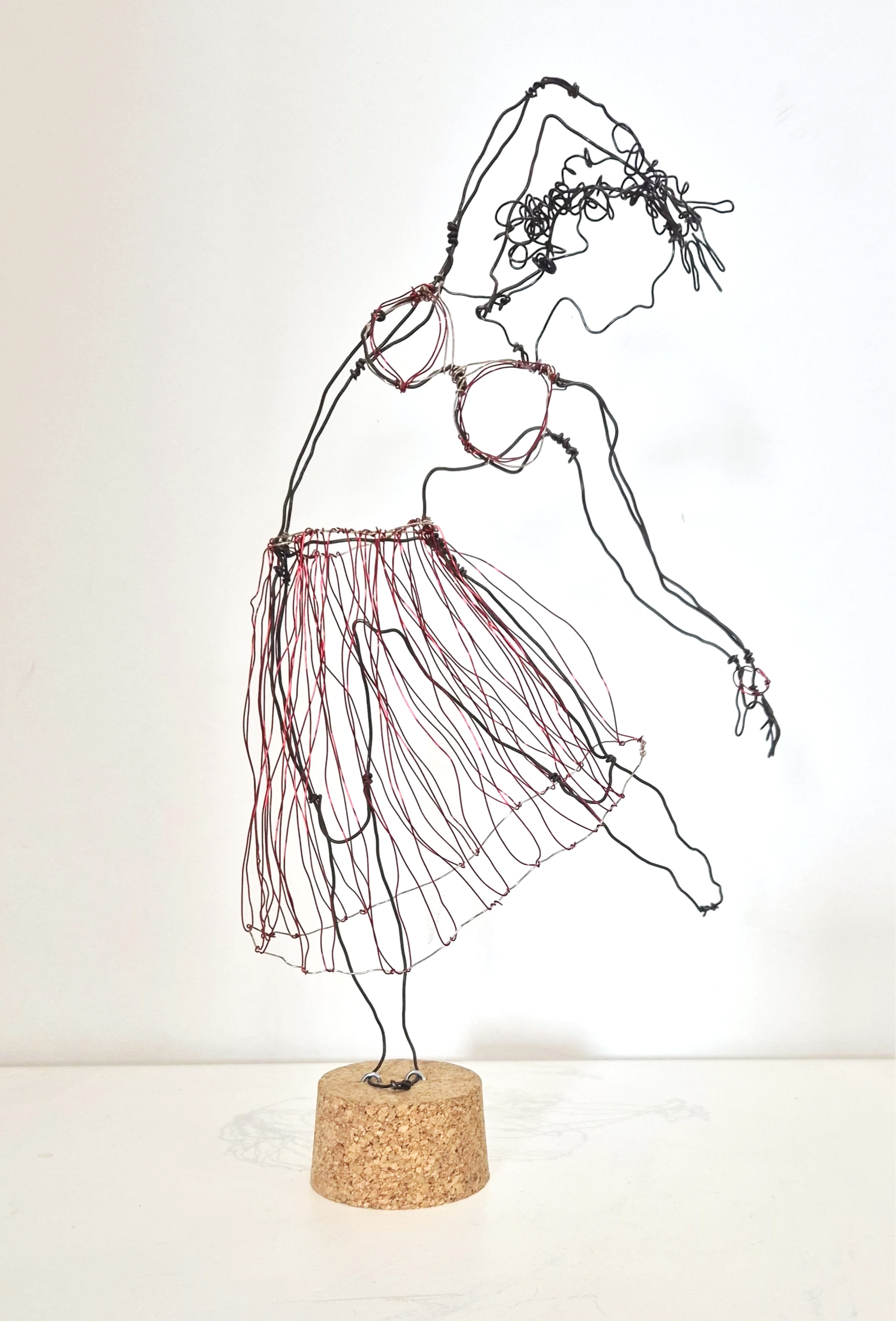 Statue en fil métallique représentant une femme danseuse portant une robe à franges, montée sur un socle en liège.