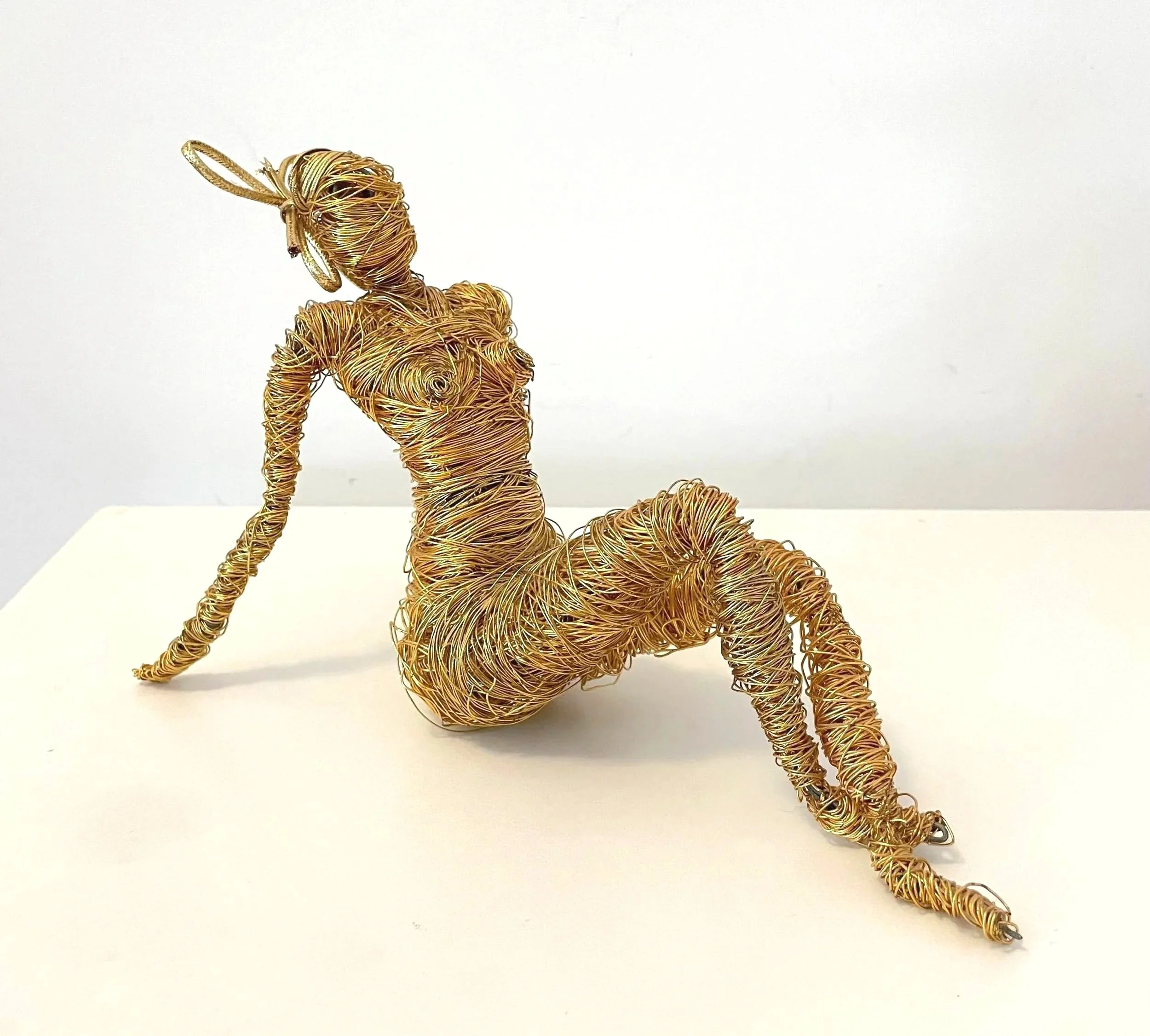 Sculpture d'une femme qui bronze, en fil de fer doré