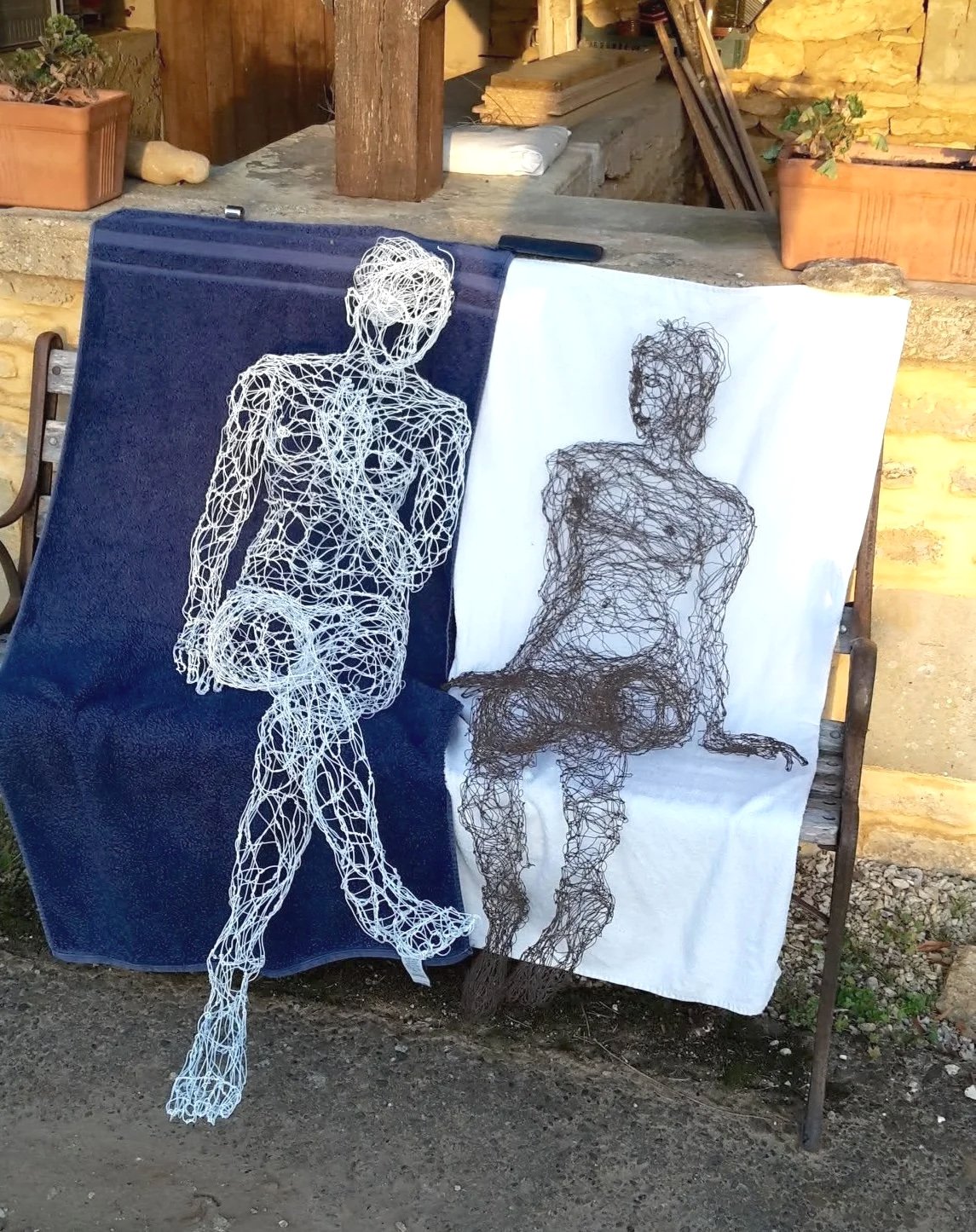 Deux sculptures de femmes assises en fil de fer recuit