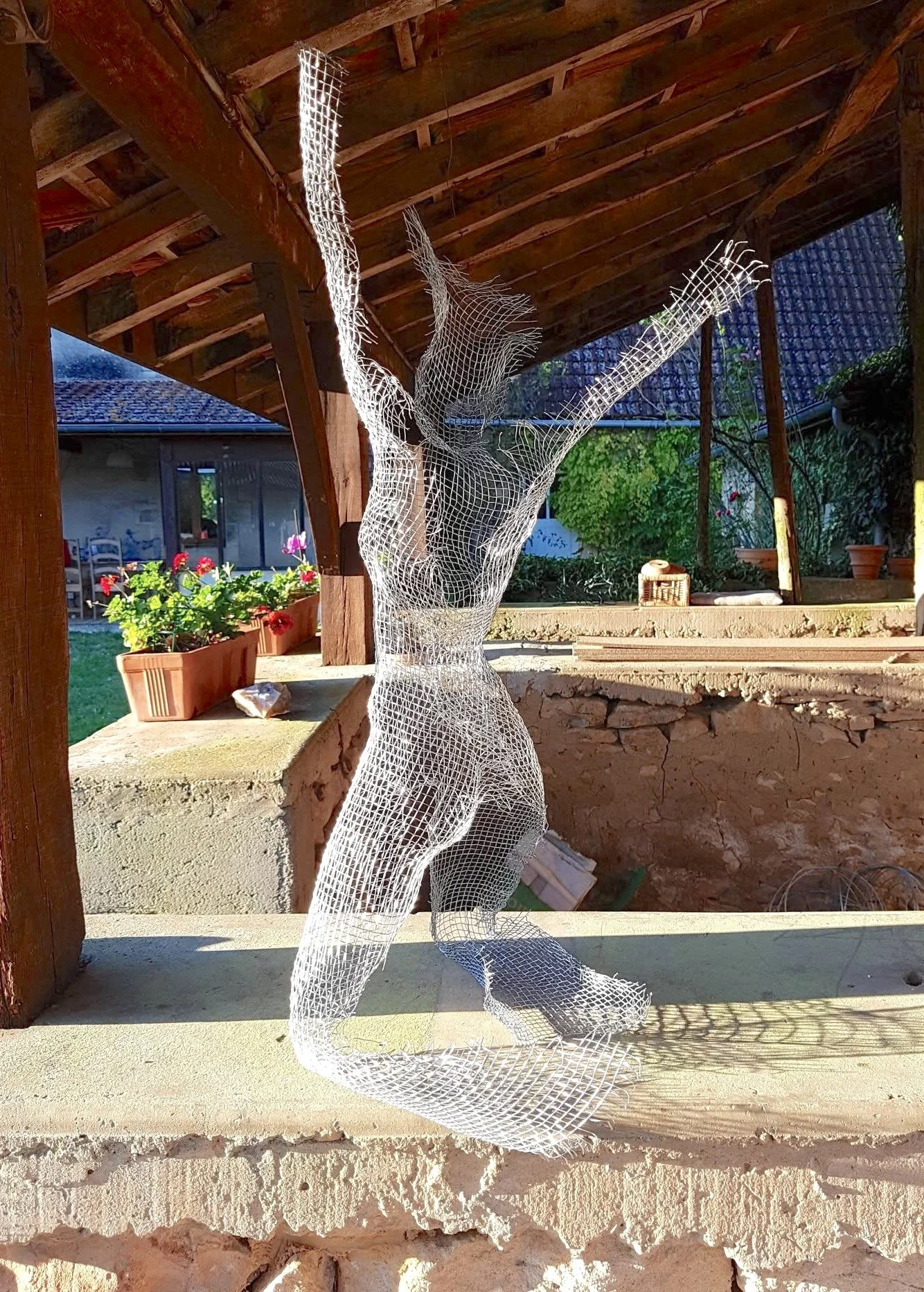 Sculpture d'une femme agenouillée de dos en grillage 