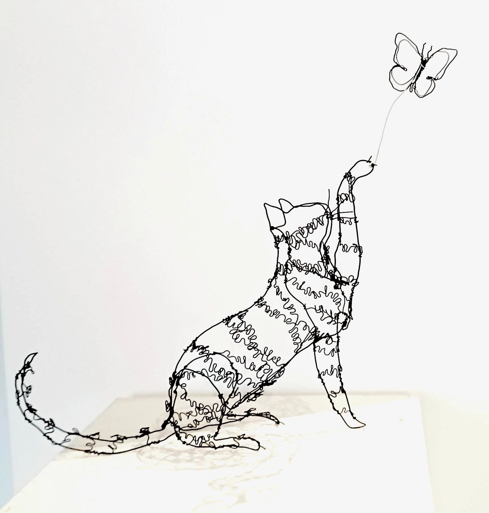 Sculpture de chat chassant un papillon, fil de fer recuit 