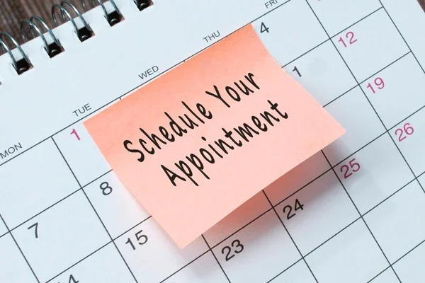 Calendar page with a pink sticky note that reads 'Schedule Your Appointment' placed on it.