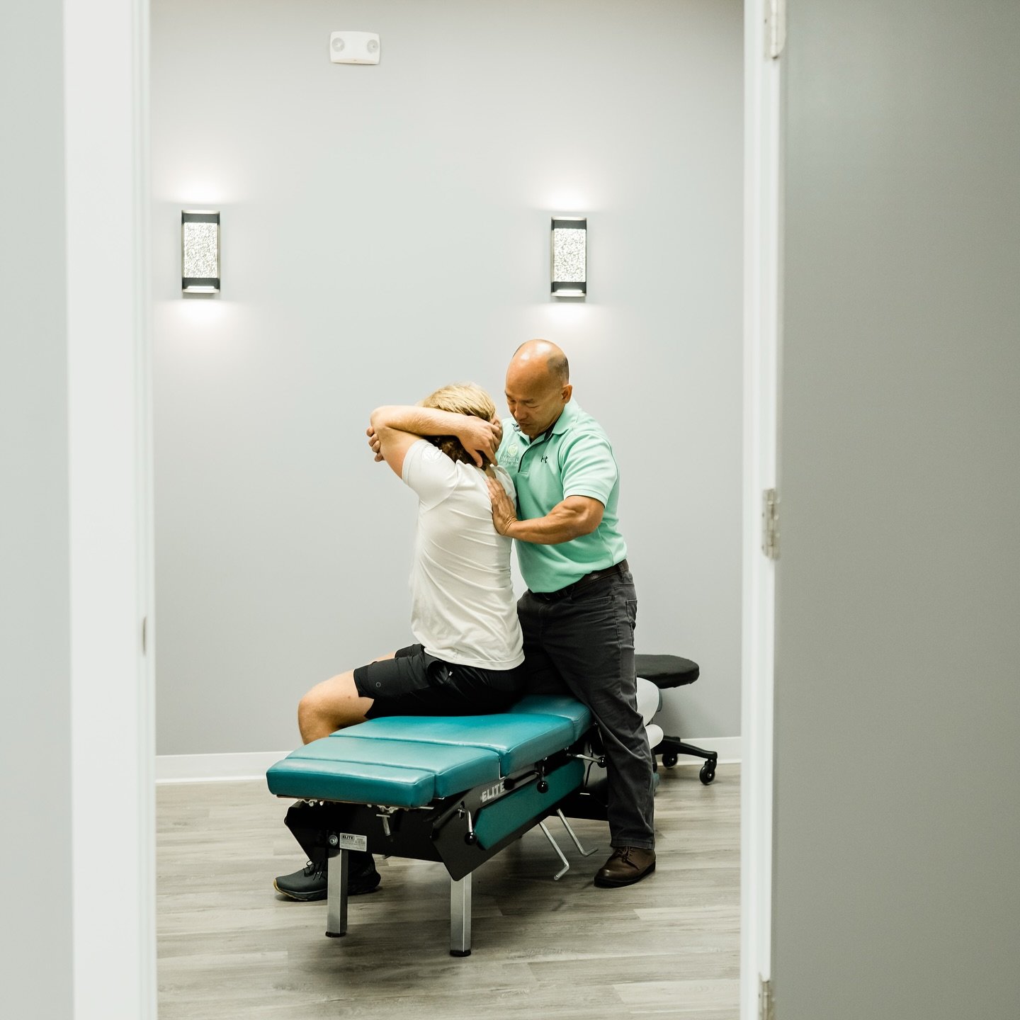 A man helping a woman with a back injury on an examination table in a medical room.