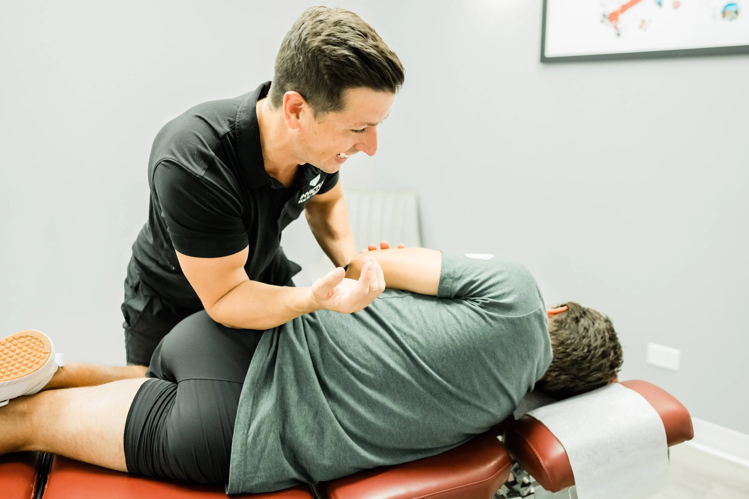 A chiropractor performs an adjustment on a patient's back in a clinic setting.