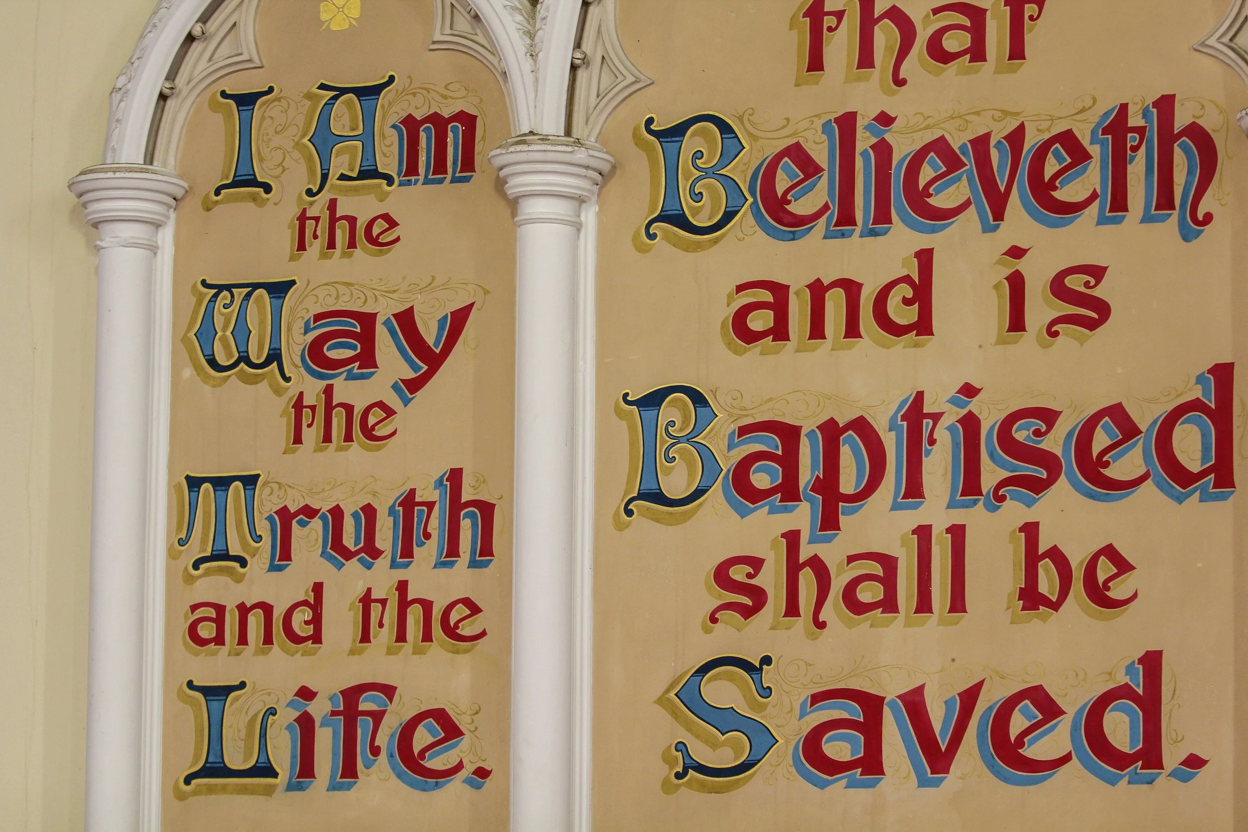 Colorful vintage style sign with decorative lettering reads 'I am the way, the truth, and the life' on a beige background with ornate white frame.