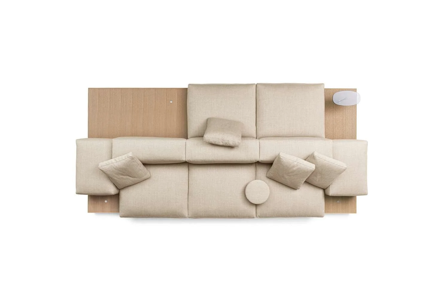Top-down view of a beige sofa with five throw pillows on a light wooden platform, with a wall-mounted light fixture on the right side.