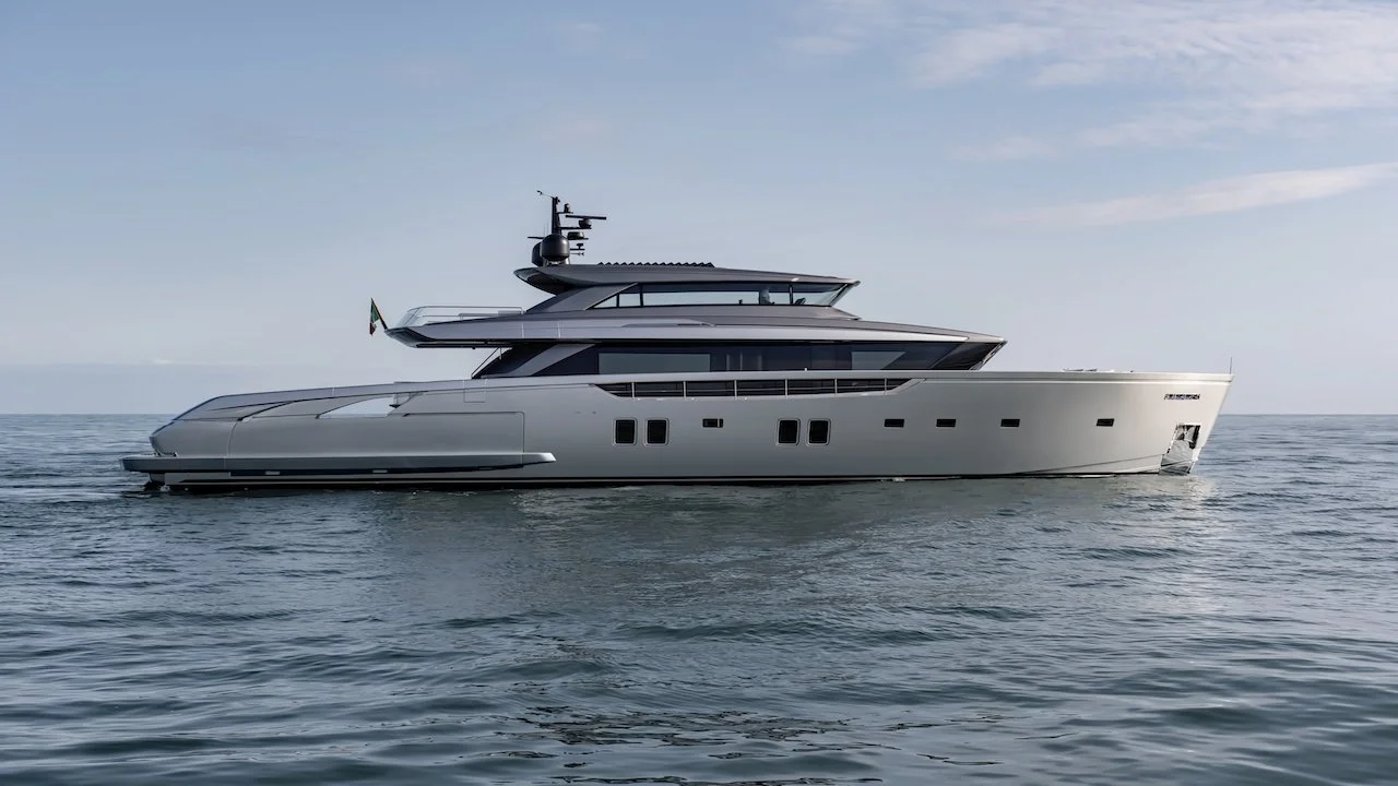 A large white luxury yacht sailing on calm ocean waters against a partly cloudy sky.