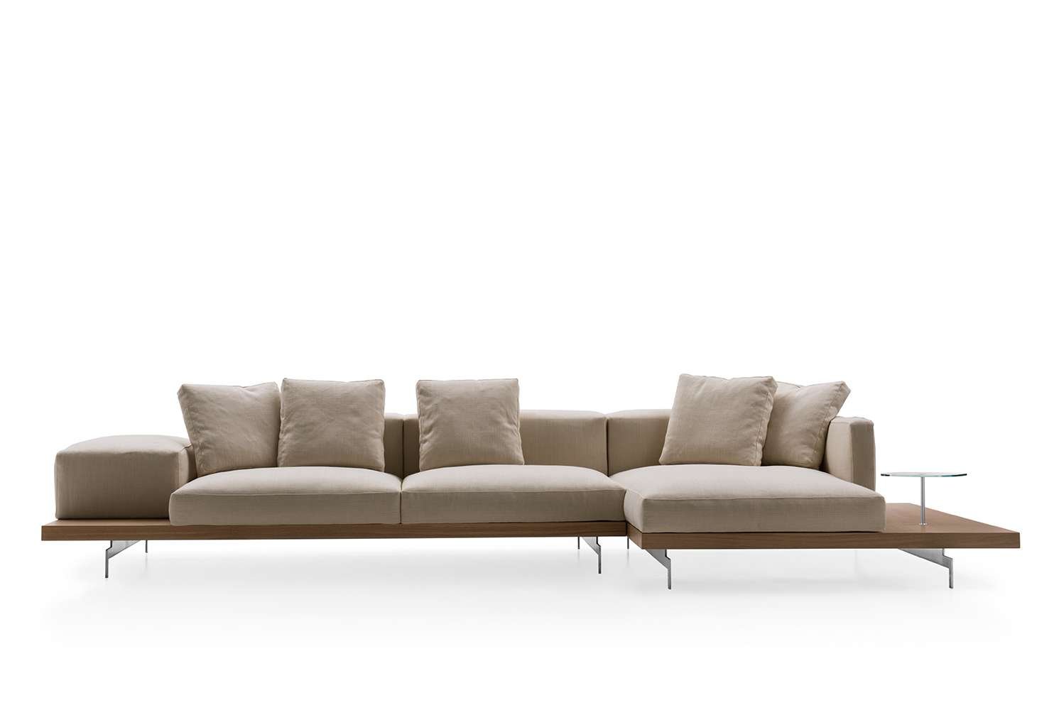 Modern beige sectional sofa with cushions and a wooden base, accompanied by a small round side table with a glass top.