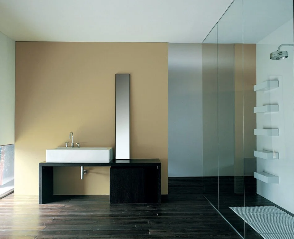 Modern bathroom with beige wall, black vanity with a white sink, a tall mirror, and a glass-enclosed shower area with a rain showerhead and white shelves.