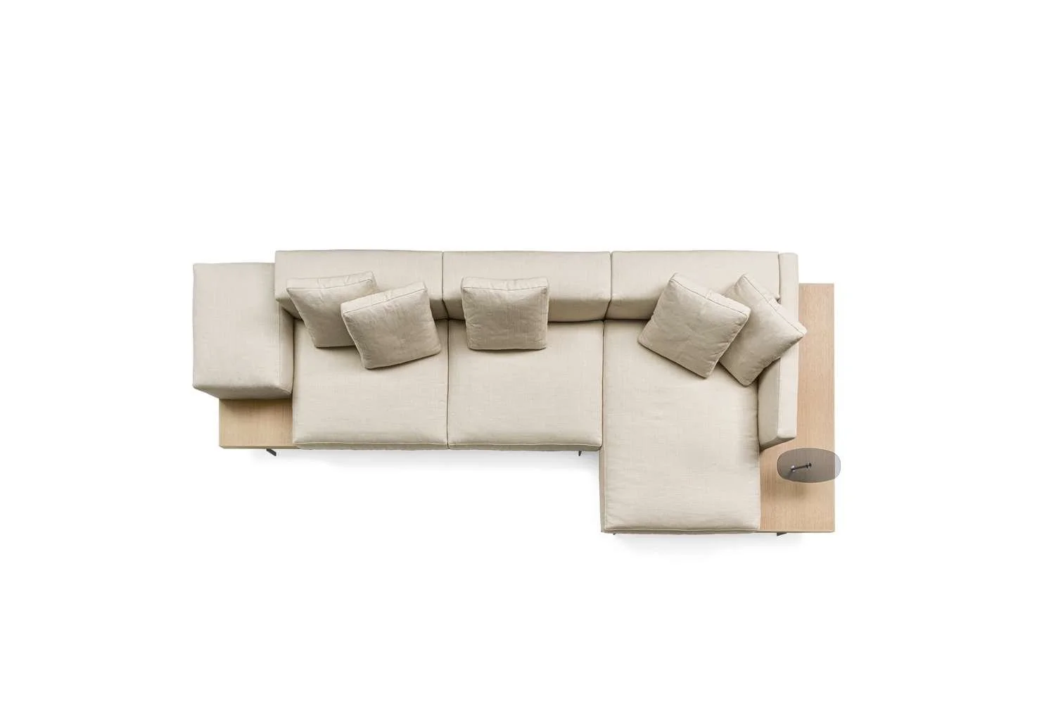 Overhead view of a beige sectional sofa with multiple matching cushions, and a small wooden side table with a gray lamp on it, against a plain white background.