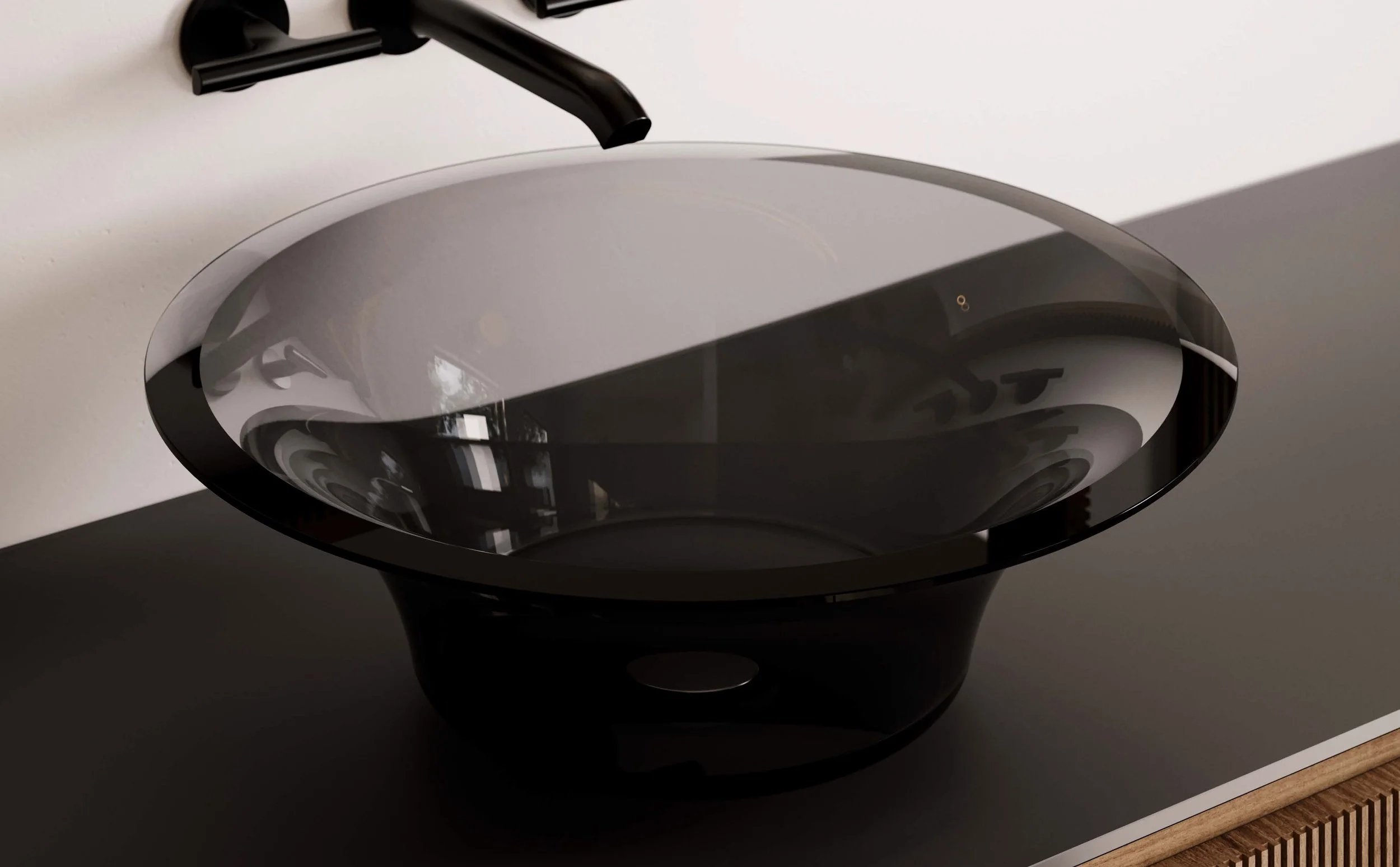 Close-up of a modern black and glass laundry or utility sink with a matte black faucet, installed on a white wall.