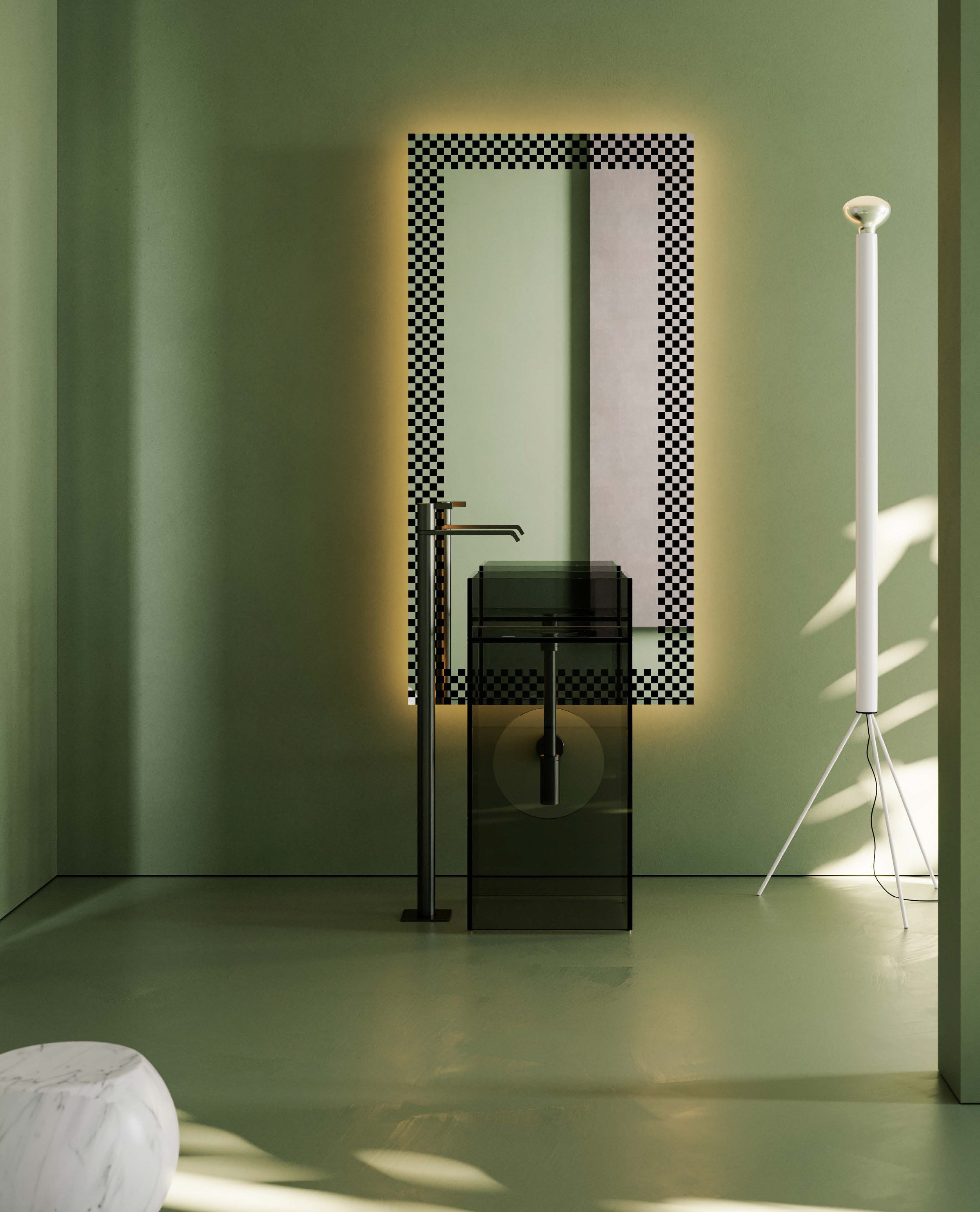 Minimalist interior with a black metal stand, a standing lamp with a metallic shade, and a light green wall with a decorative mirror frame featuring black and white checkerboard pattern.