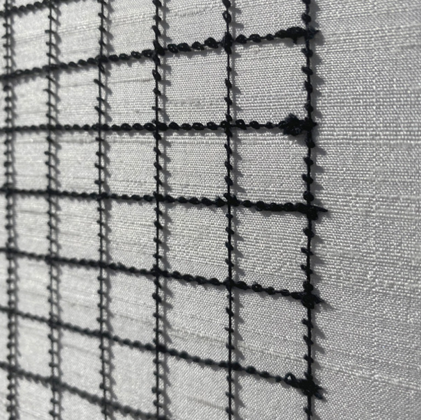 Close-up of a window screen with a grid pattern and a textured curtain background.