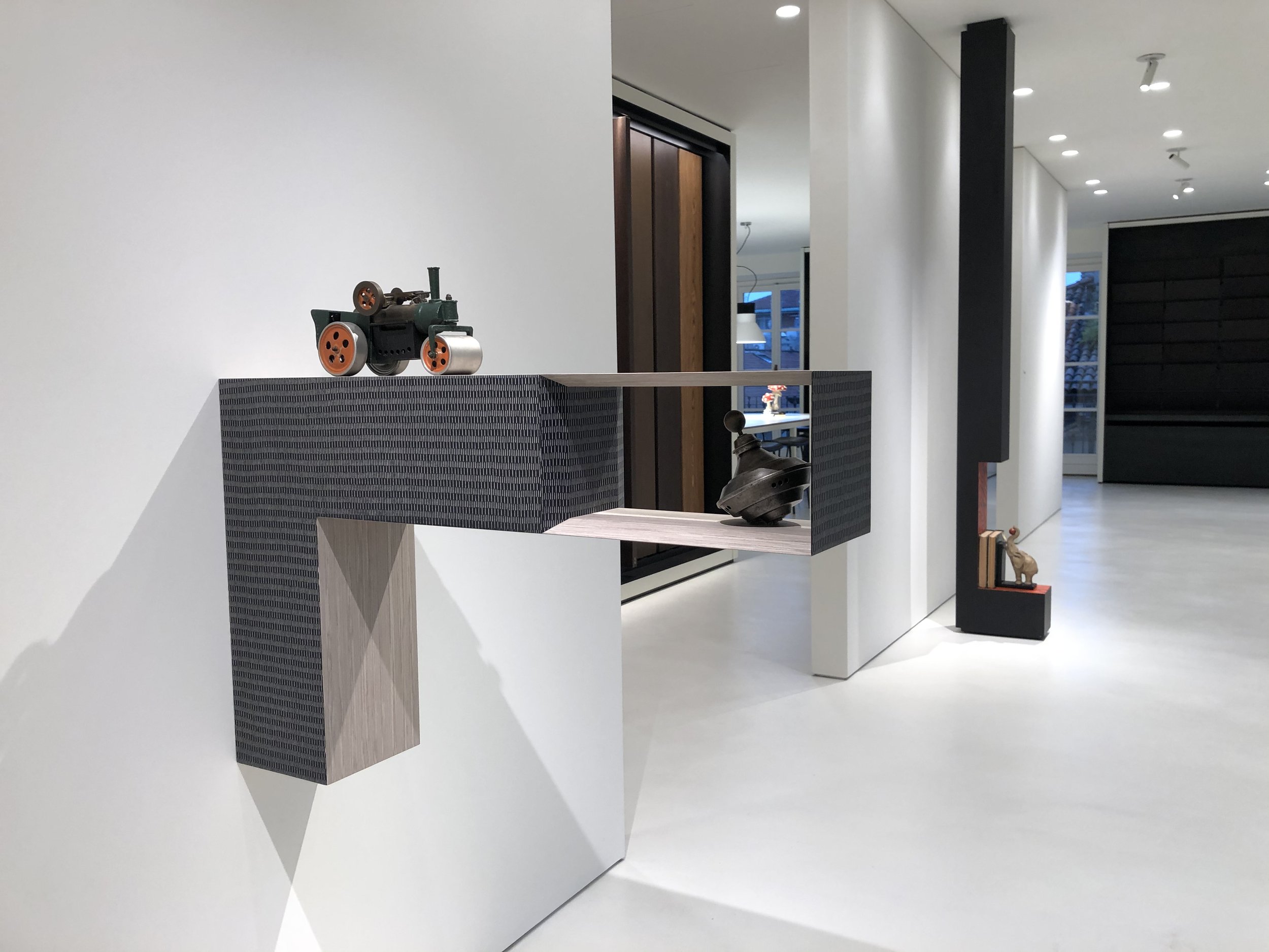 Modern interior with white walls, black pillar, and decorative sculptures on display.