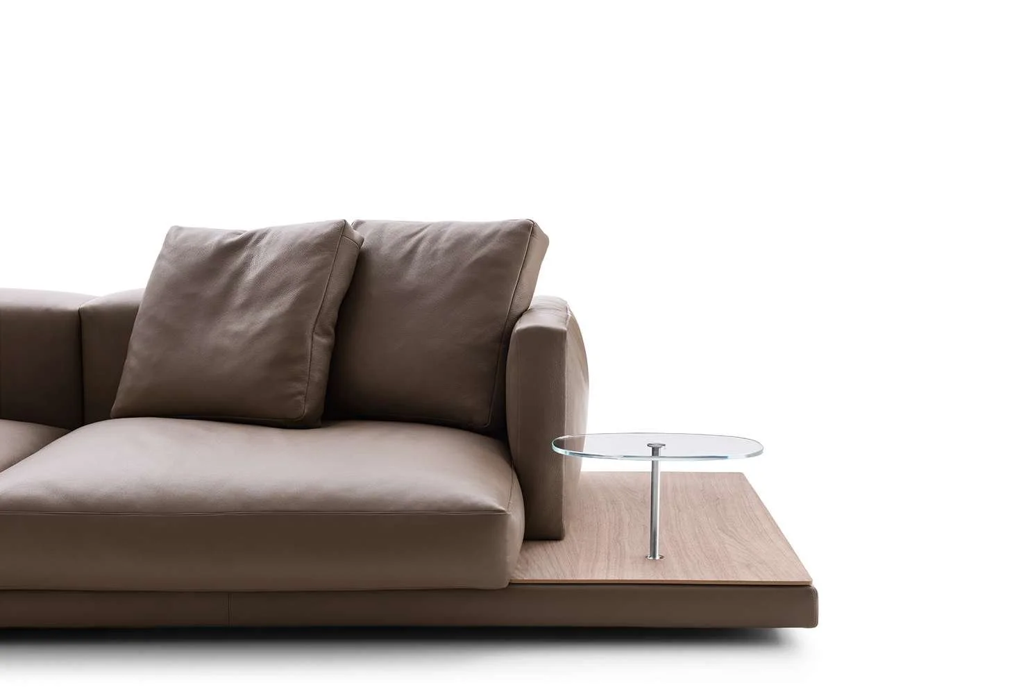 Modern beige sofa with two cushions and a wooden side table with a glass top on a white background.