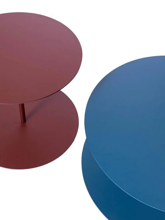 Close-up of two nested round tables, one pink and one blue, with a minimalistic white background.