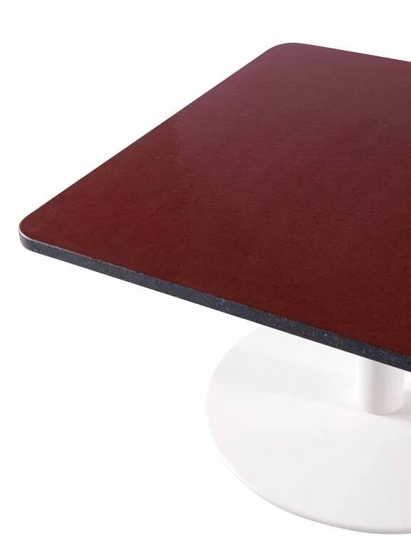 Close-up view of a rectangular table with a red wood grain top and a white pedestal base.
