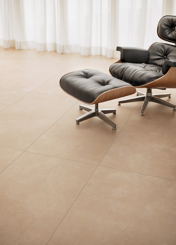 Modern black leather lounge chair with matching ottoman on metal base in front of white curtains, on beige tiled floor.