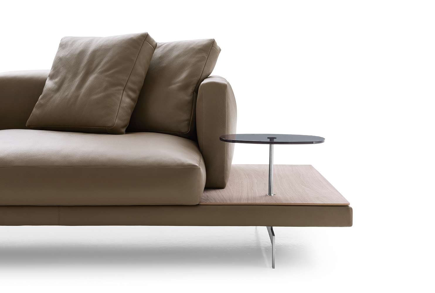 Modern beige sofa with two large cushions and a small attached side table with black top and metal support.