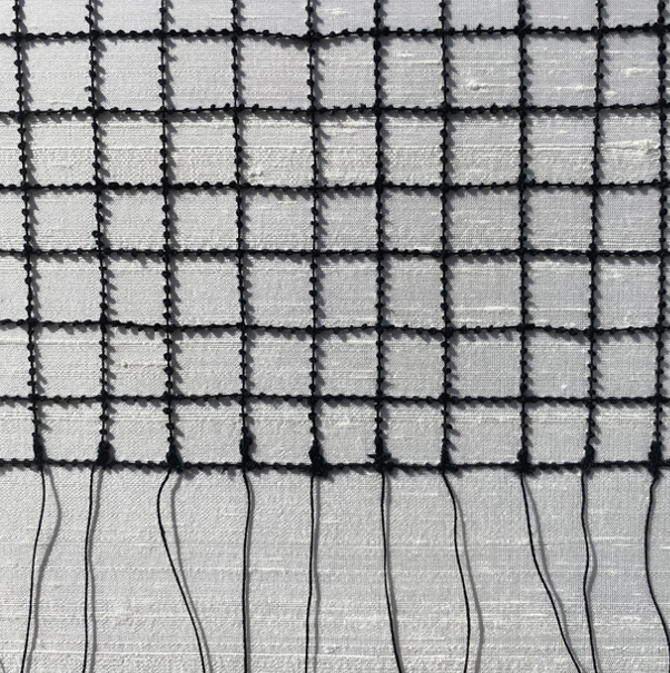 Close-up of a mosquito screen with a metal grid and black plastic or silicone framing.
