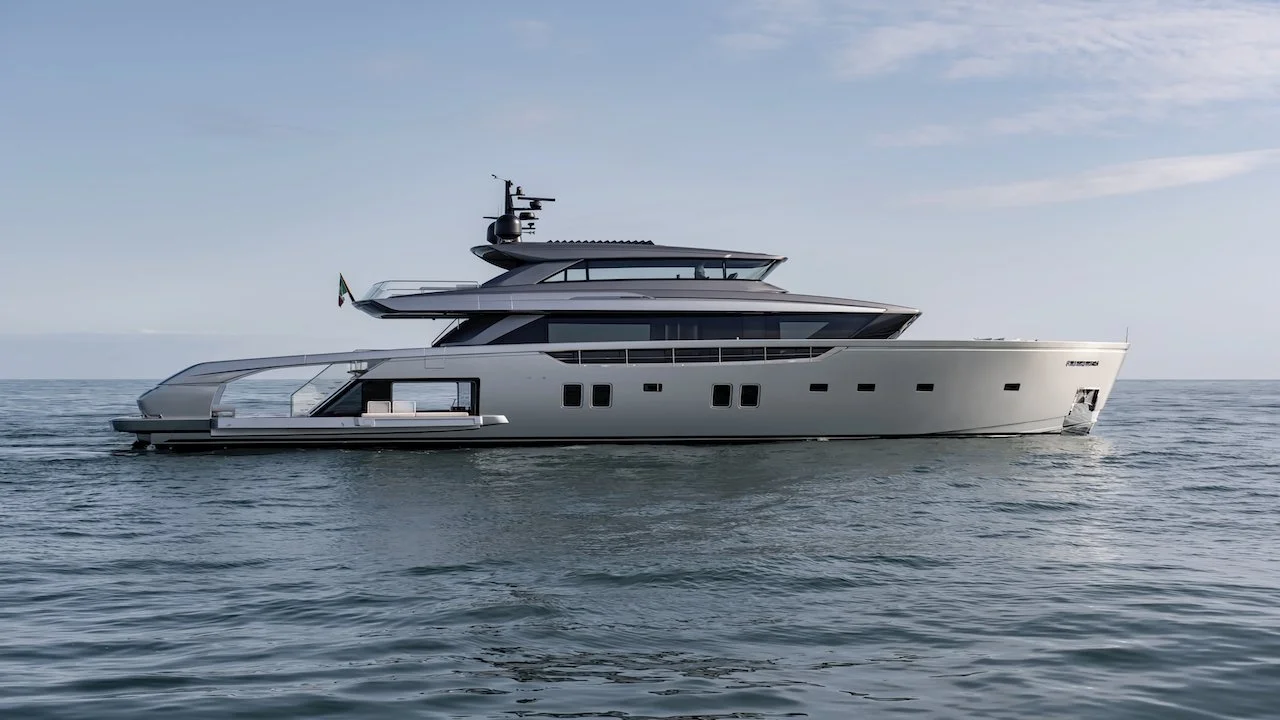 A sleek, modern yacht floating on calm ocean waters under a partly cloudy sky.