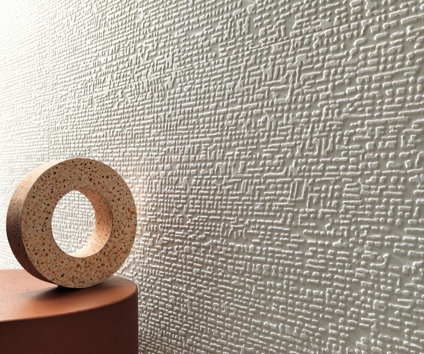 Decorative cork-style circular object on a pink platform in front of a textured white wall.