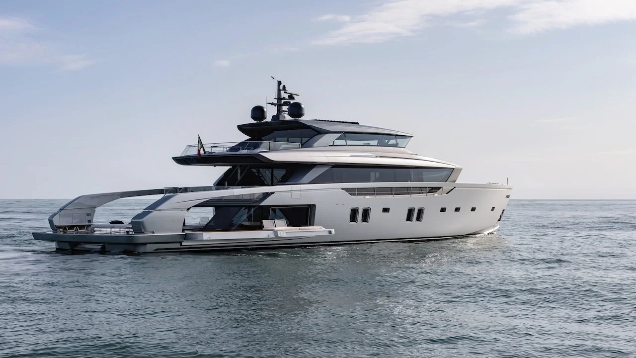 A modern white yacht sailing on open water with a clear sky overhead.