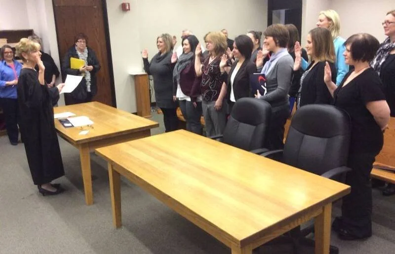 Group of women taking an oath during a swearing-in ceremony in a conference room.