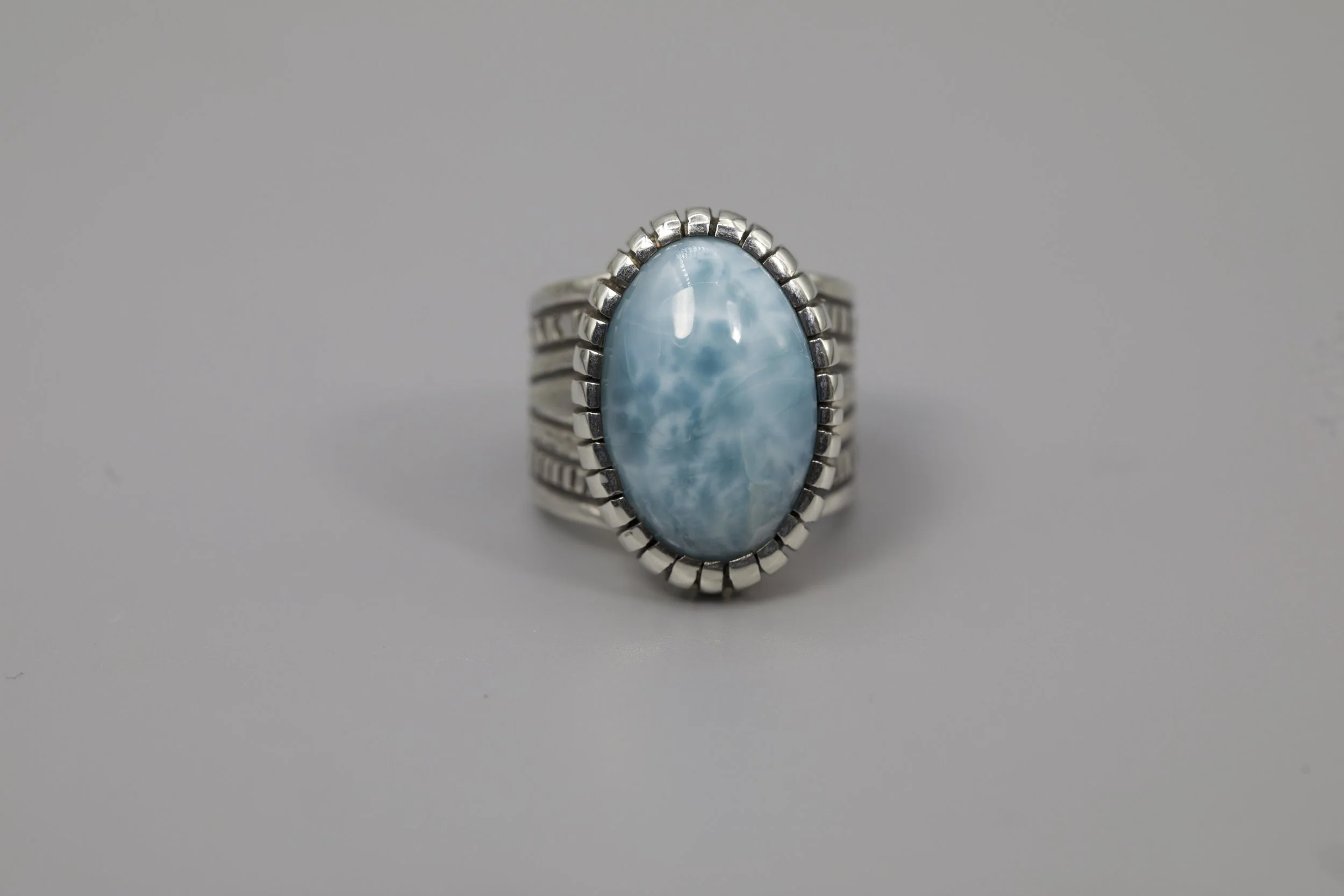A silver ring with a large, oval, light blue gemstone set in the center.