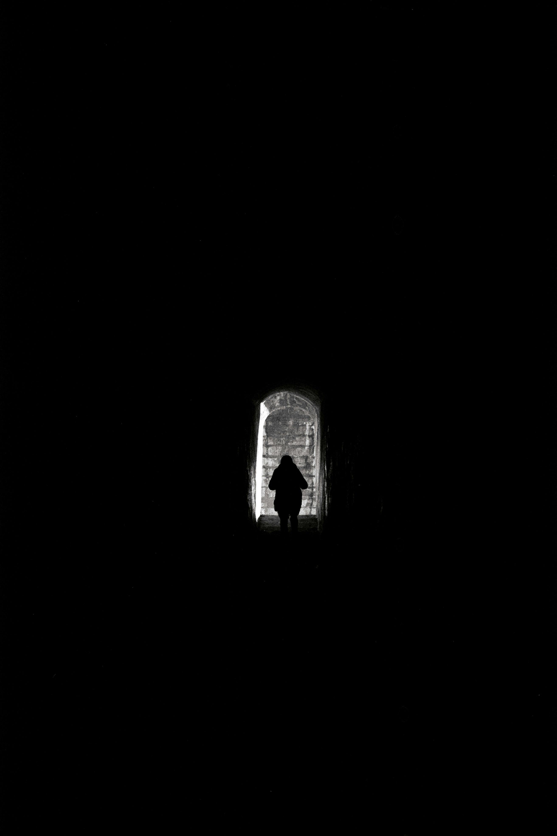 Man walking in a dark tunnel towards the light