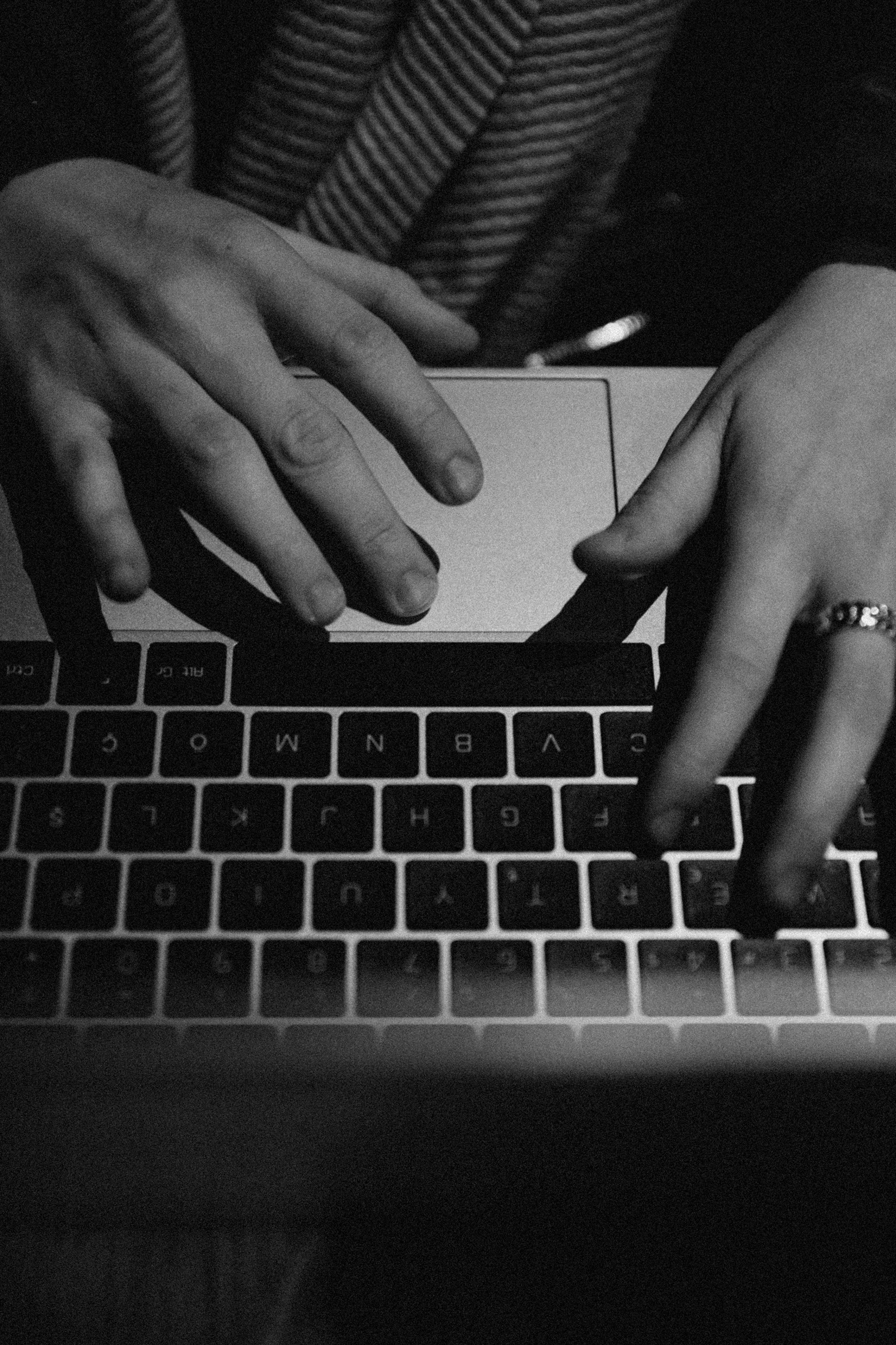 Black and white photo of hands typing on a laptop keyboard.