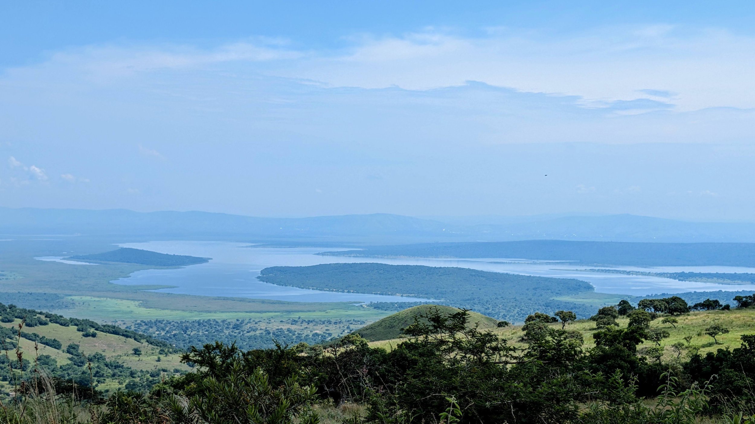 A panoramic view of a lake with several islands, surrounded by green hills and trees, under a partly cloudy sky.

Akagera National Park, Rwanda.
