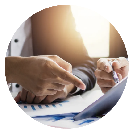 Two people discussing business documents and charts with a tablet at a desk.