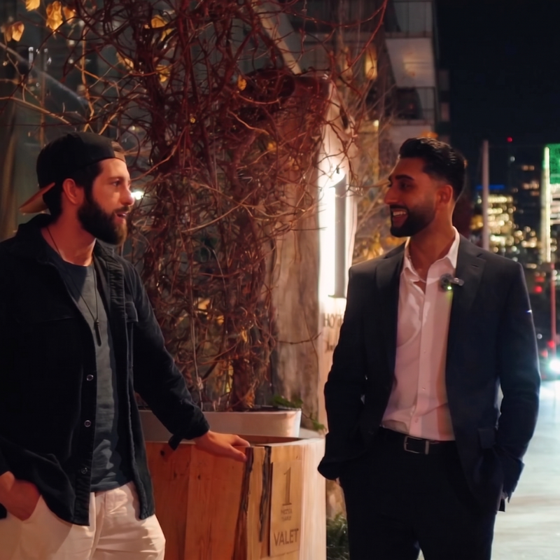 Two tech founders networking on a Toronto street at night, one casually dressed and the other in a suit.