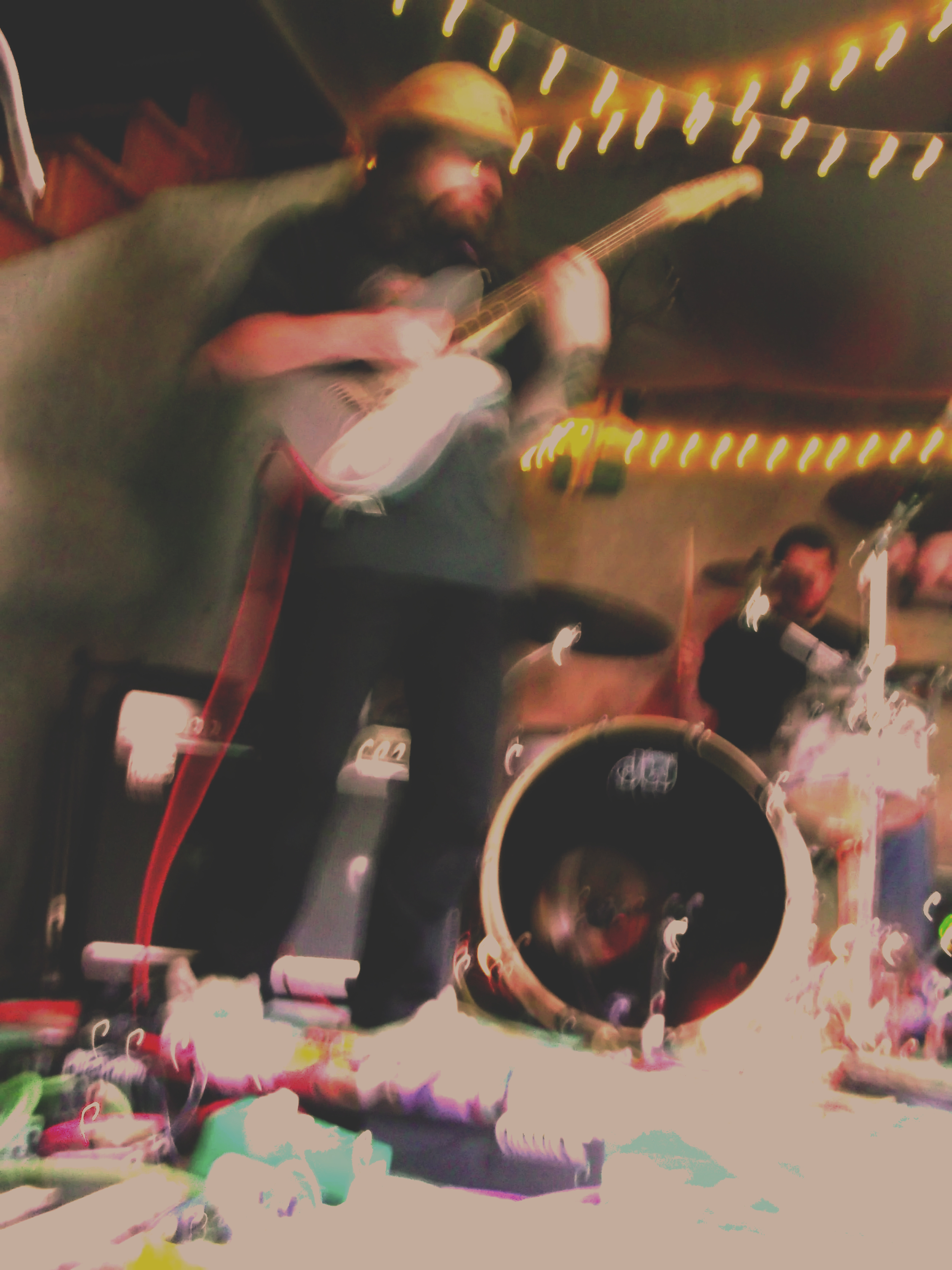 A person playing an guitar at a party, surrounded by string lights and colorful decorations.