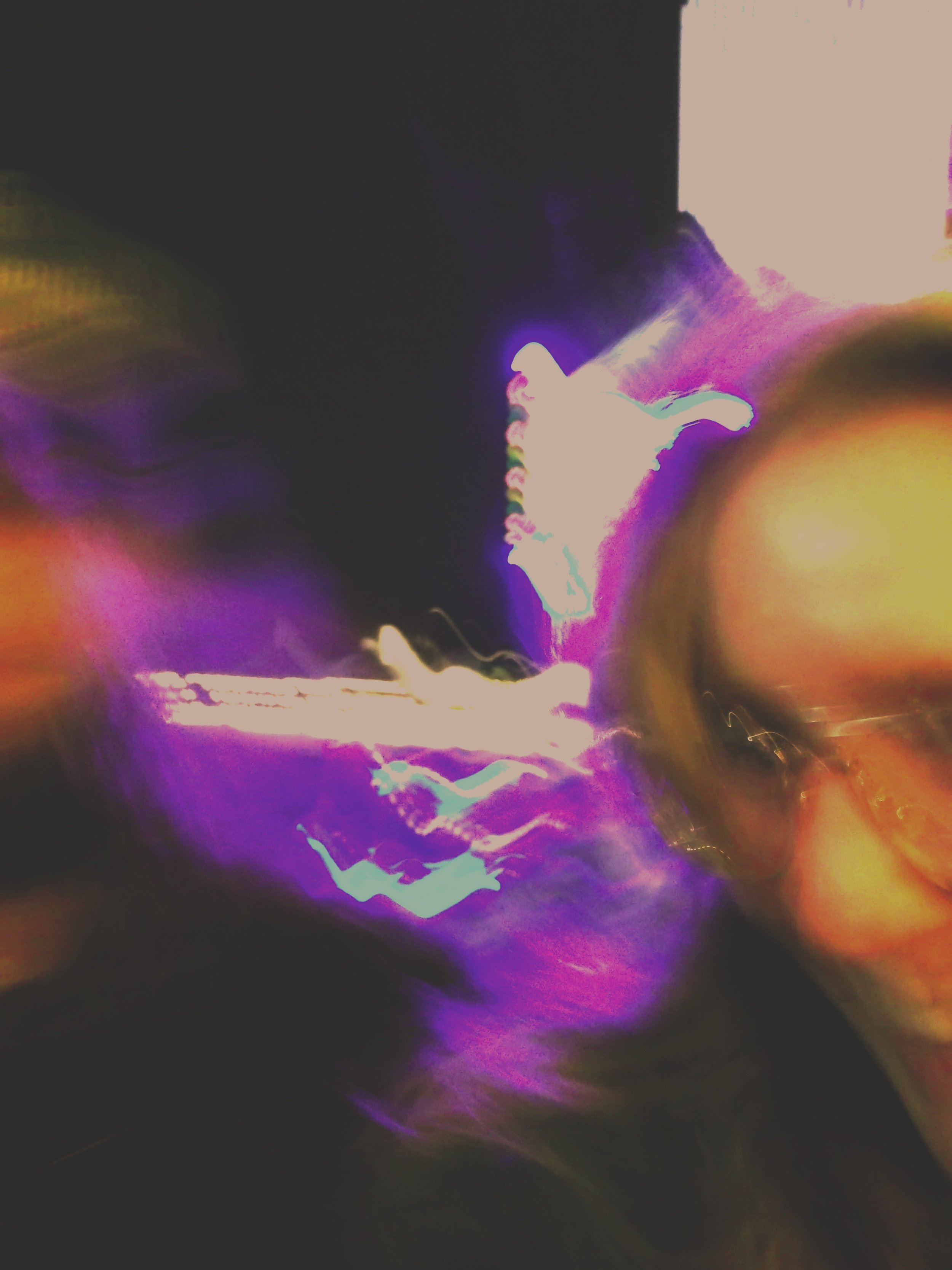Abstract image with dark background and bright streaks of purple, yellow, pink, and orange light.