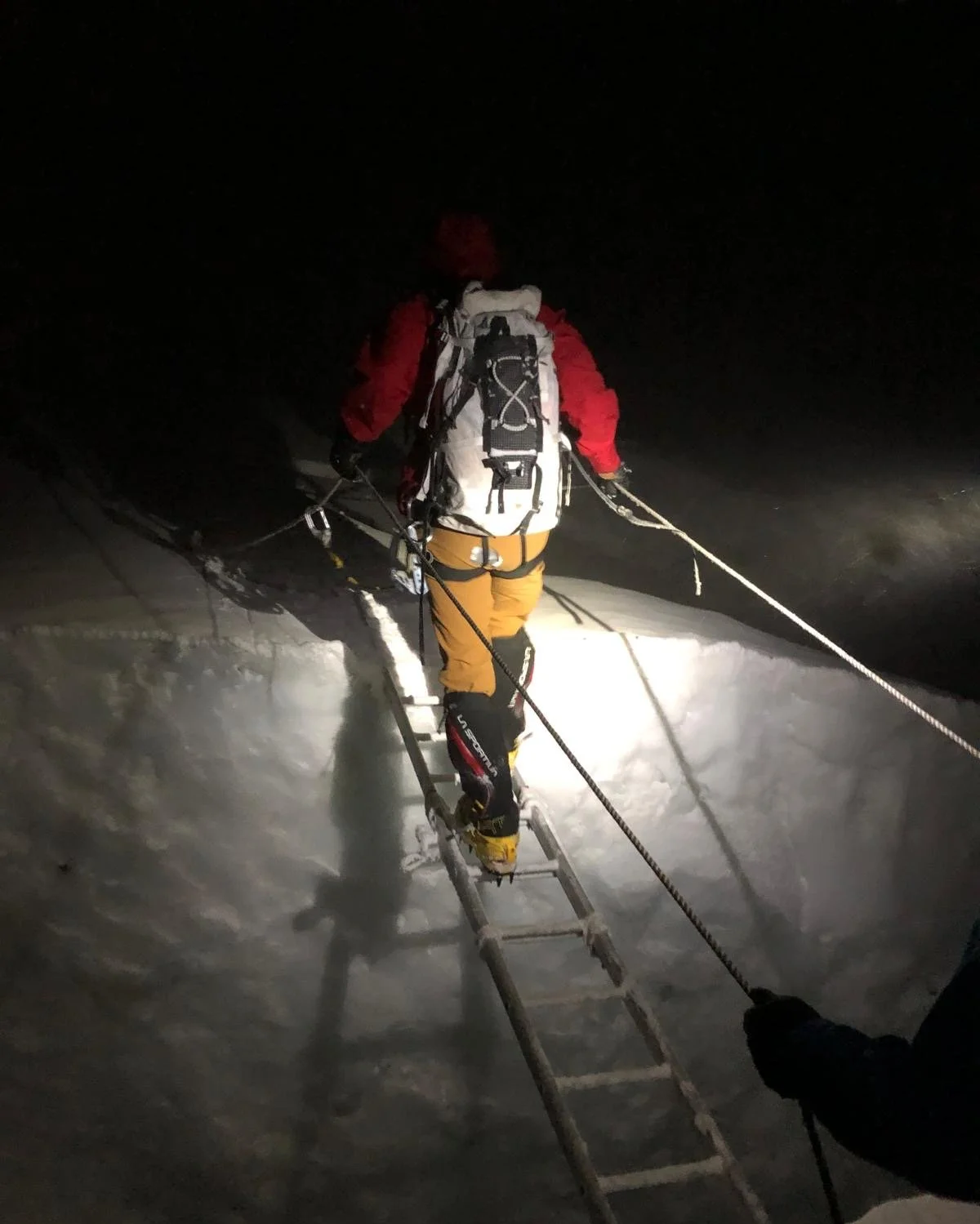 Dr. Jon Kedrowski crosses a crevasse in the dark in one of his high-altitude expeditions.