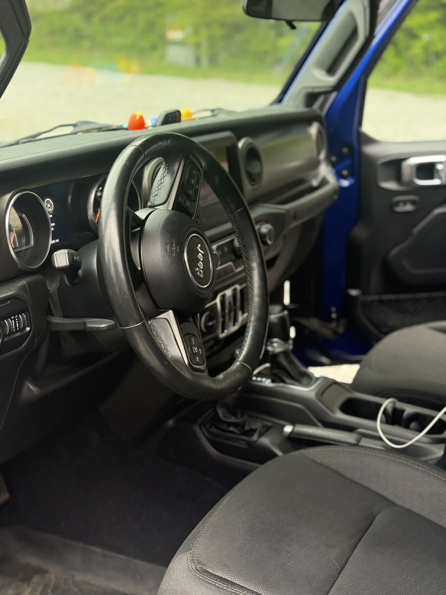 Interior view of a Jeep vehicle showing the steering wheel, dashboard, and passenger seat with cloth upholstery.