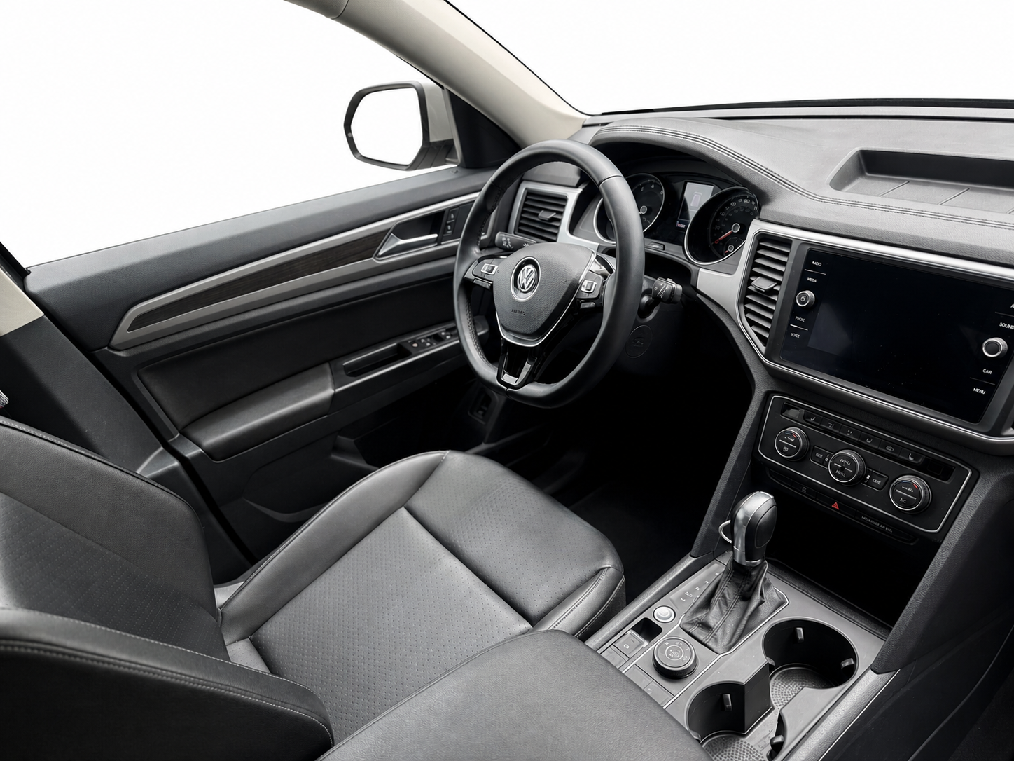 Interior of a Volkswagen vehicle, showing the steering wheel, dashboard, center console, gear shift, and front passenger seat.